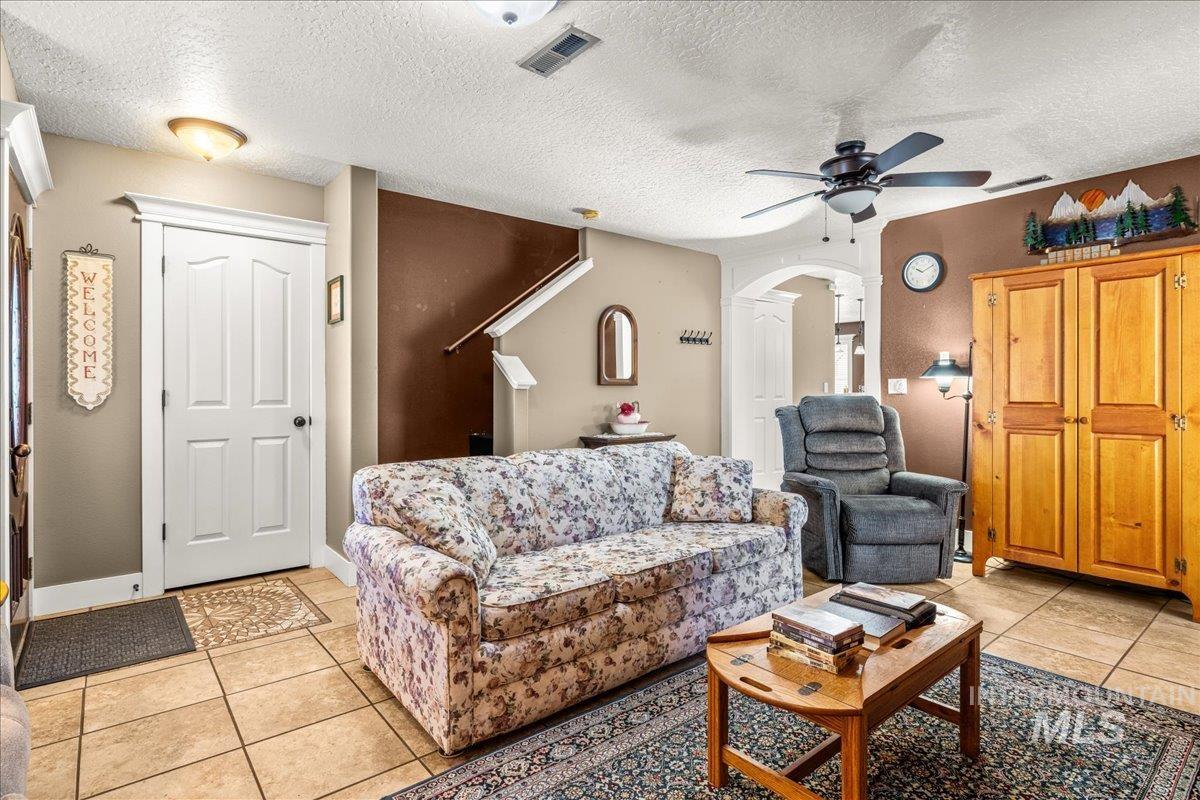 Living area with light tile patterned flooring, a textured ceiling, and ceiling fan