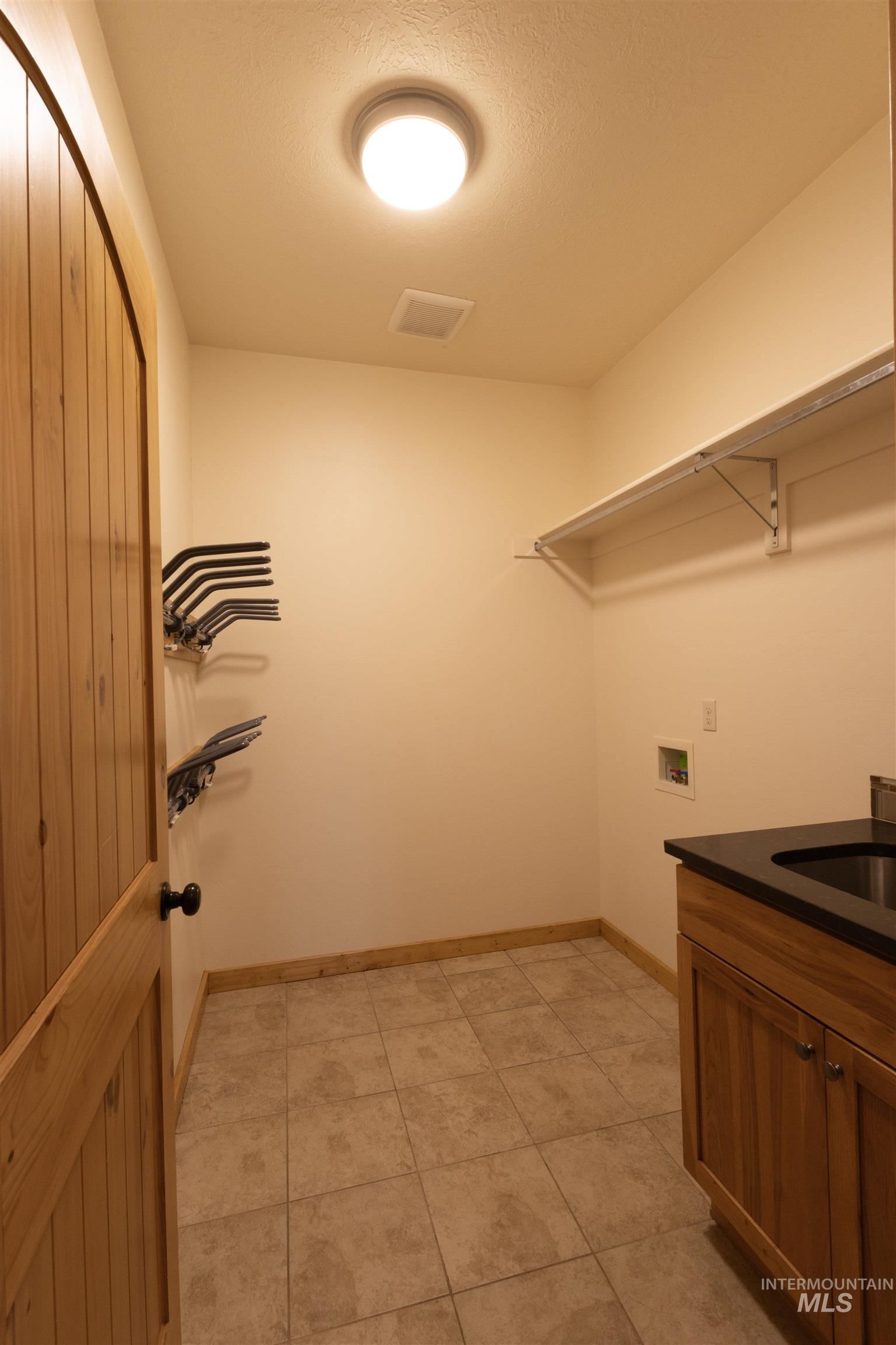 Washroom with hookup for a washing machine, light tile patterned flooring, and a textured ceiling