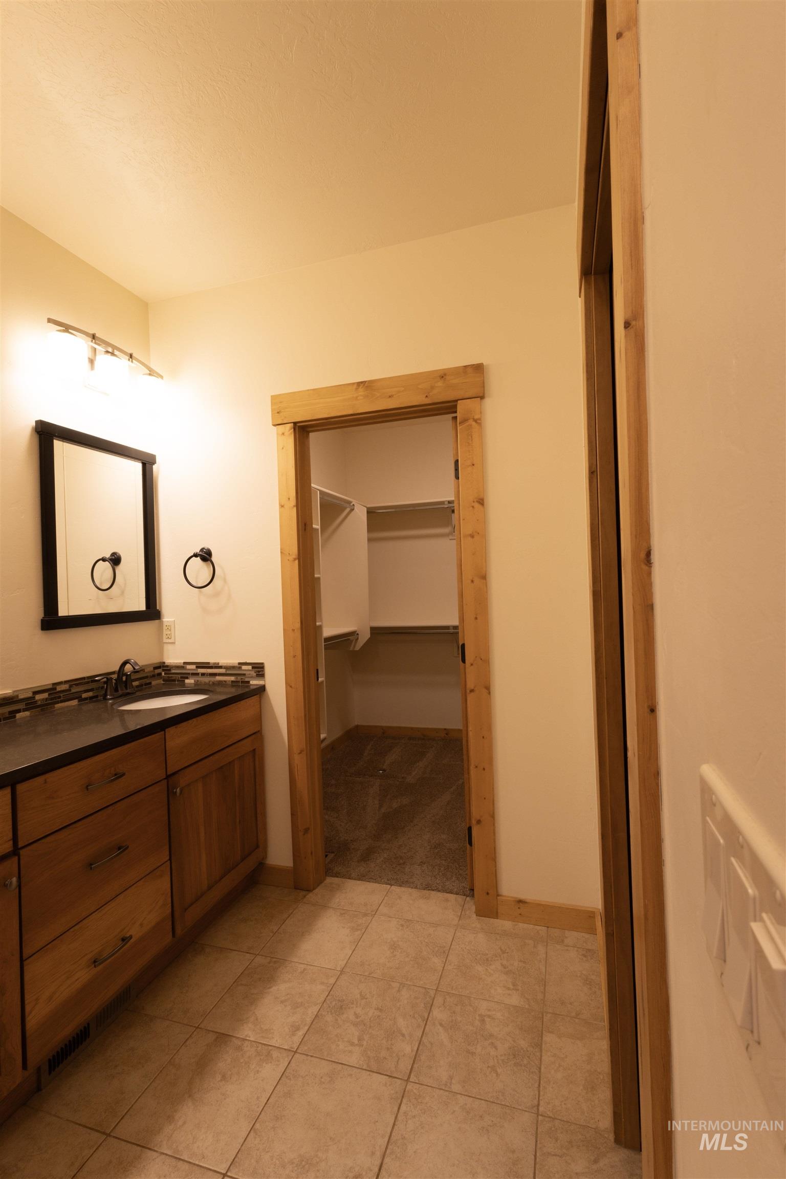 Bathroom with vanity, a spacious closet, and light tile patterned floors
