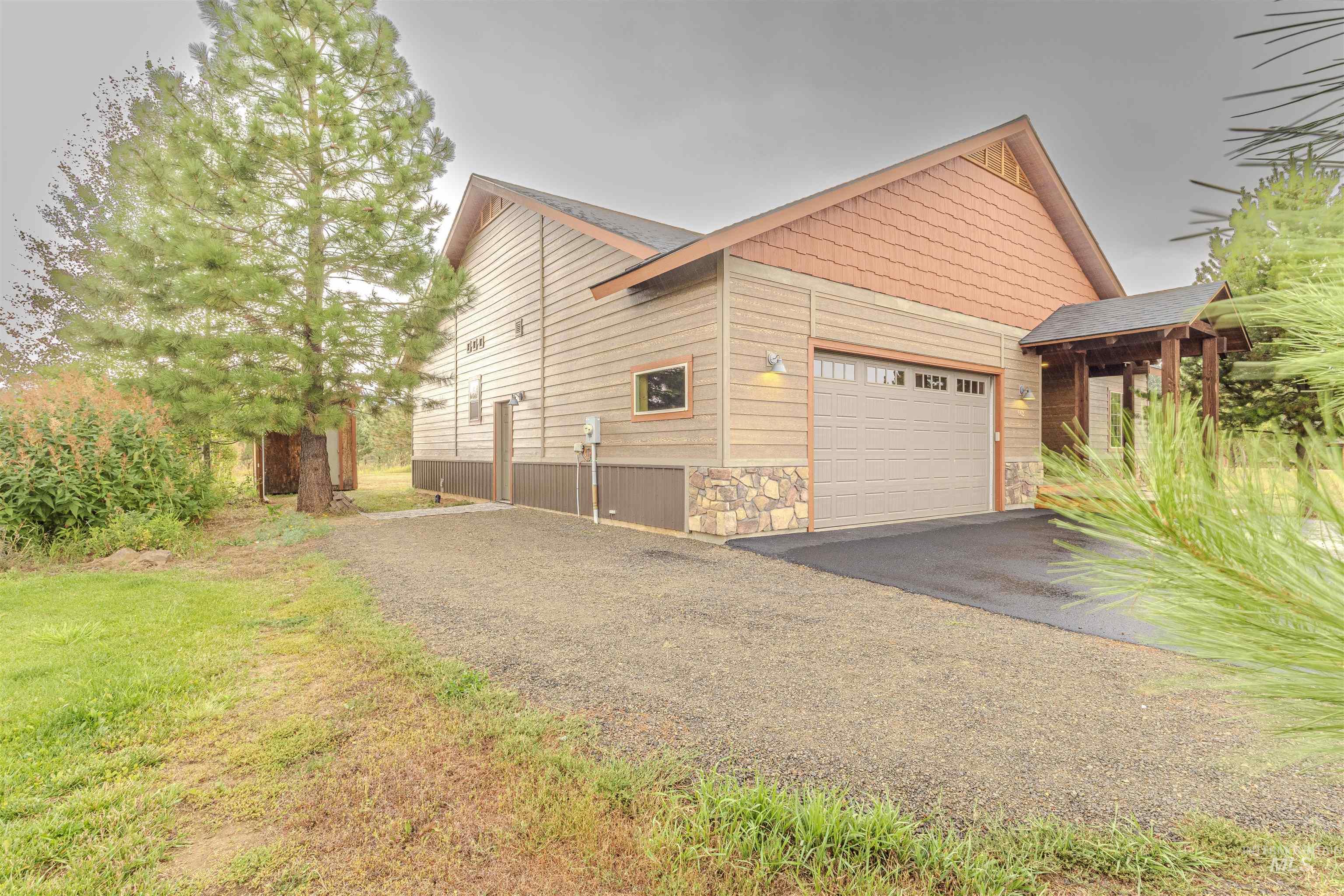 View of side of property featuring stone siding, asphalt driveway, and a garage