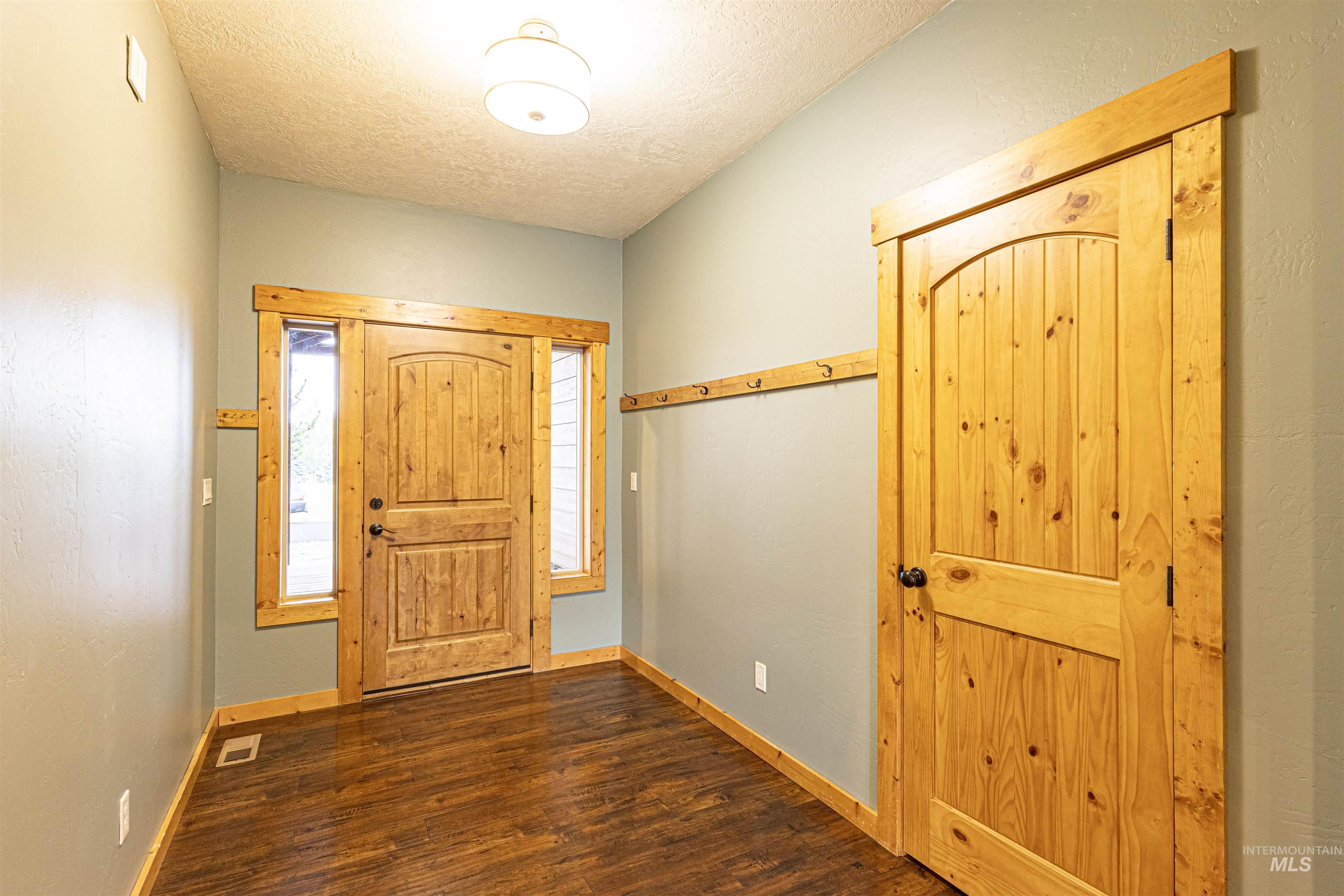 Entrance foyer featuring a textured ceiling and dark wood finished floors