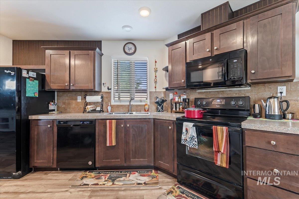 Kitchen with black appliances, light countertops, tasteful backsplash, and dark brown cabinets