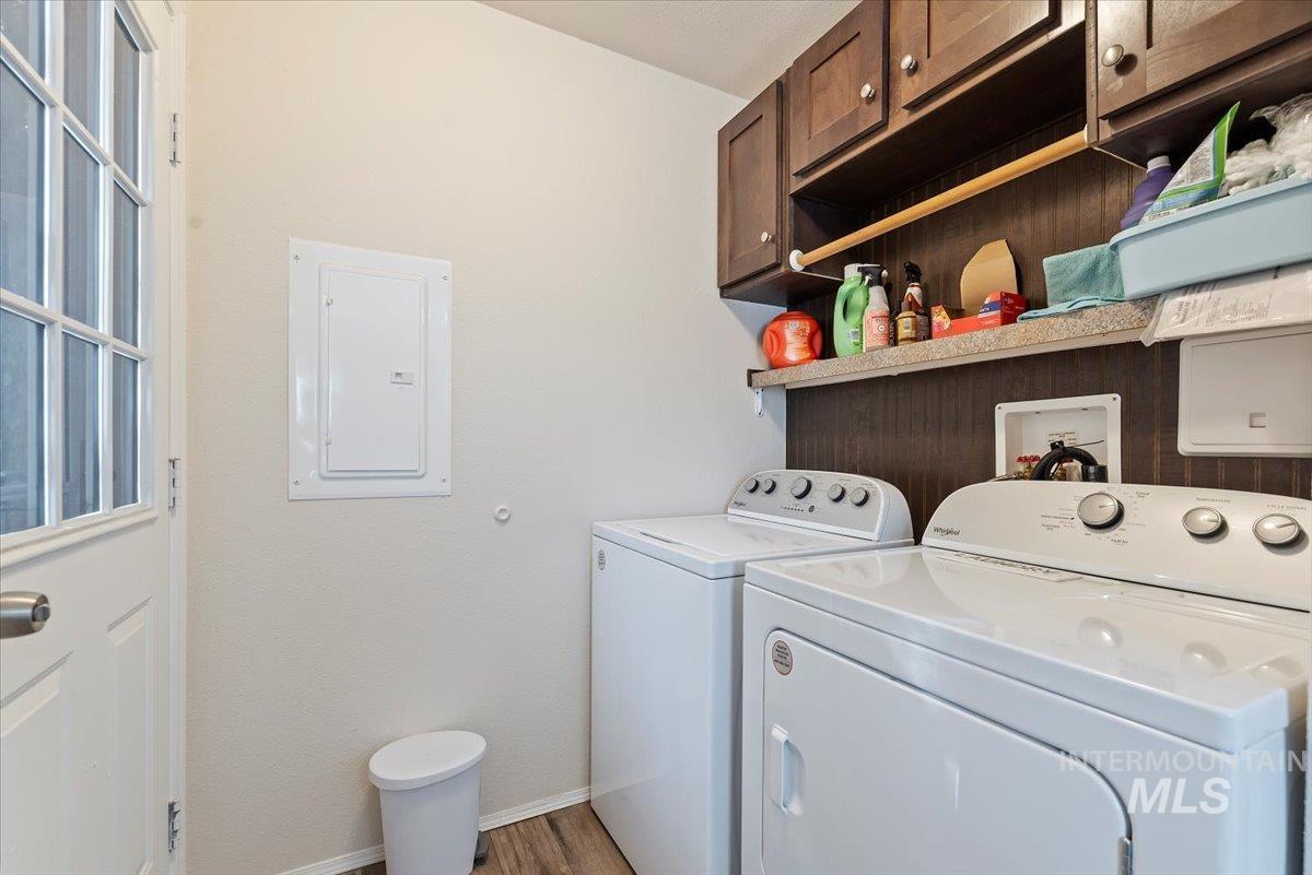 Laundry area featuring cabinet space, electric panel, washing machine and dryer, and wood finished floors