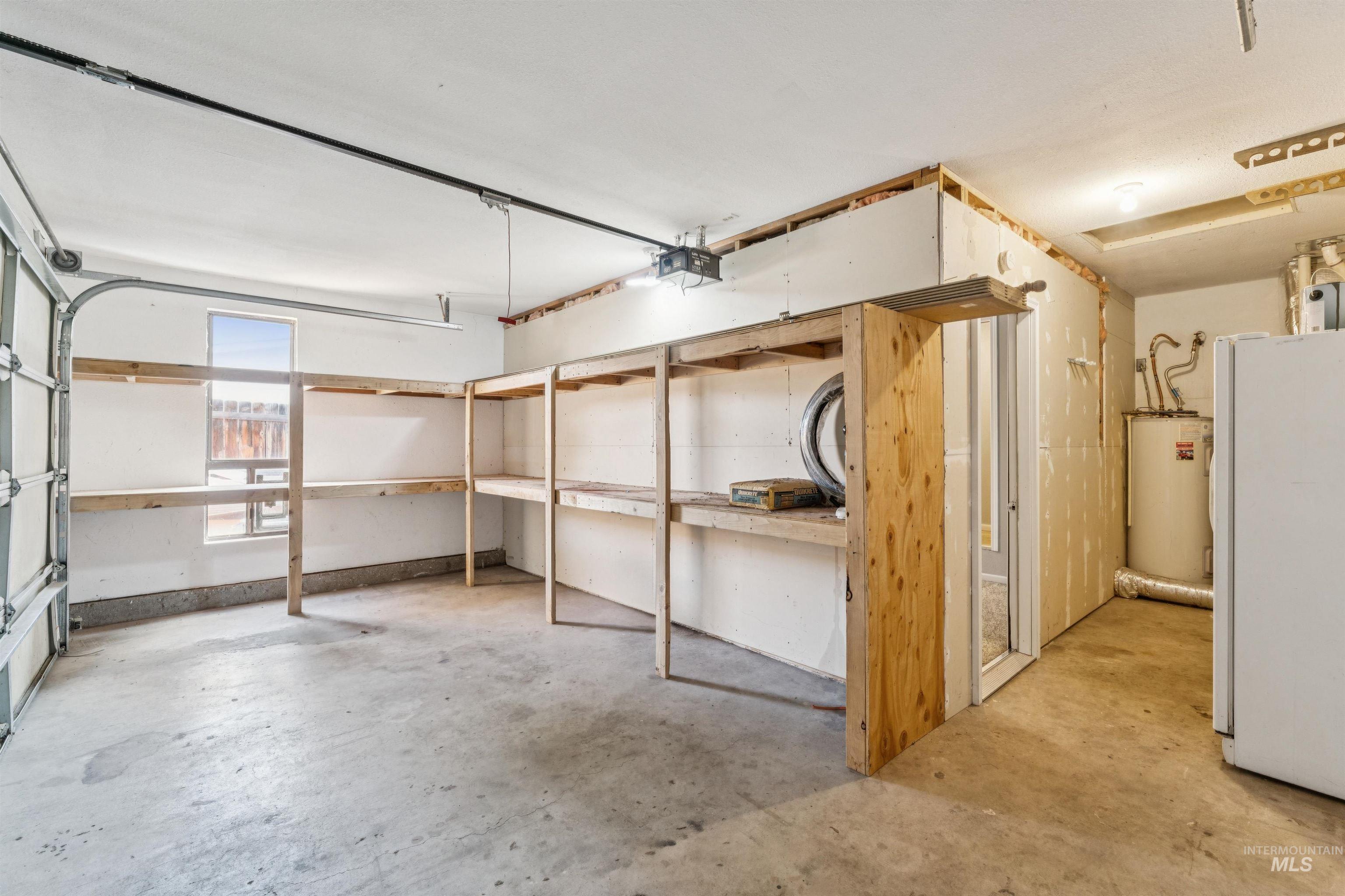 Below grade area with freestanding refrigerator, a garage, and electric water heater