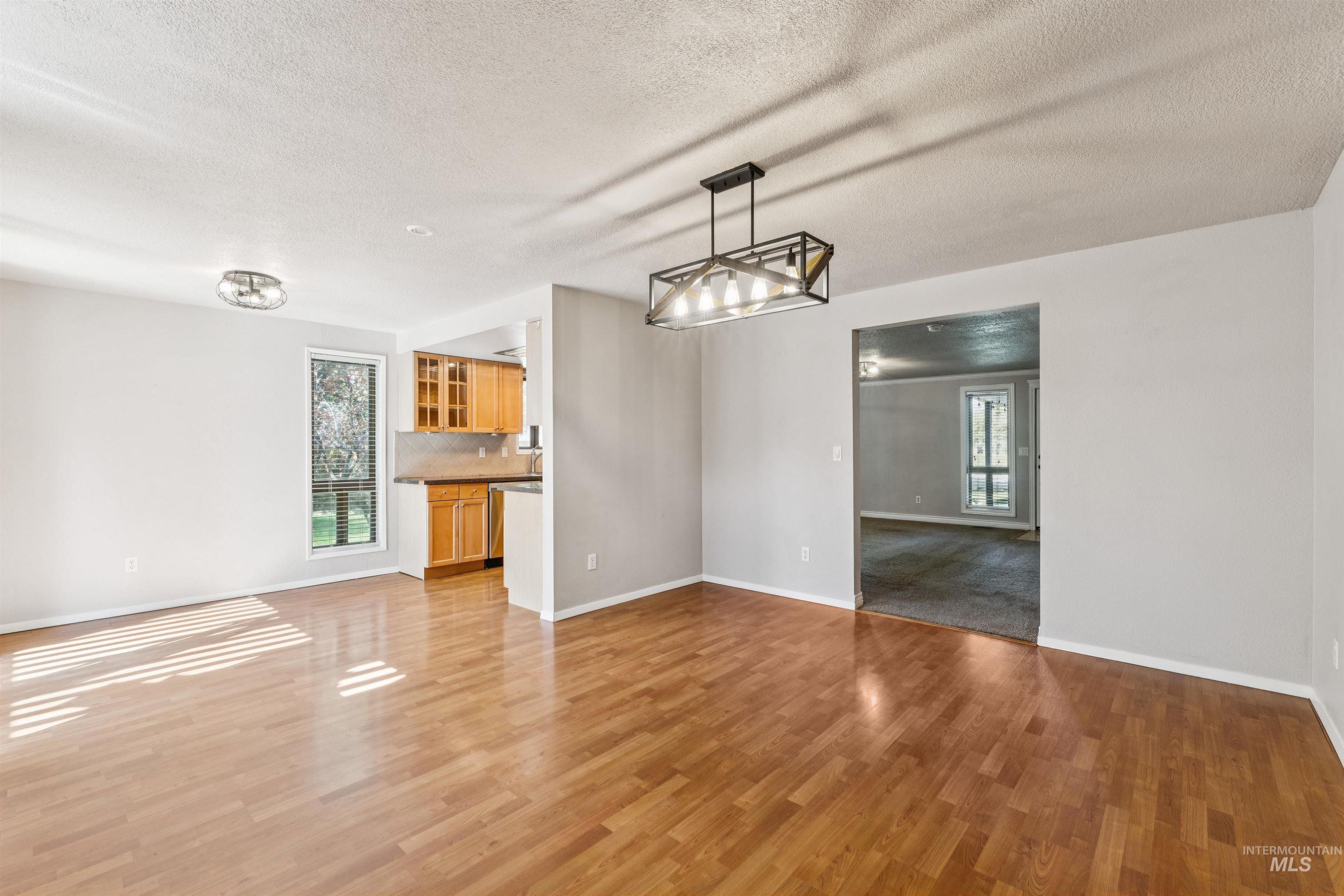 Unfurnished dining area featuring a textured ceiling, light wood-style flooring, and a chandelier