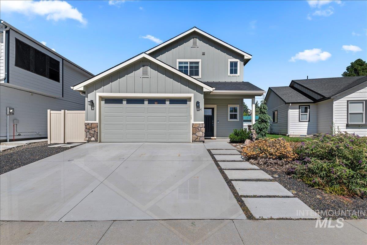 Craftsman-style home featuring stone siding, board and batten siding, driveway, and covered porch