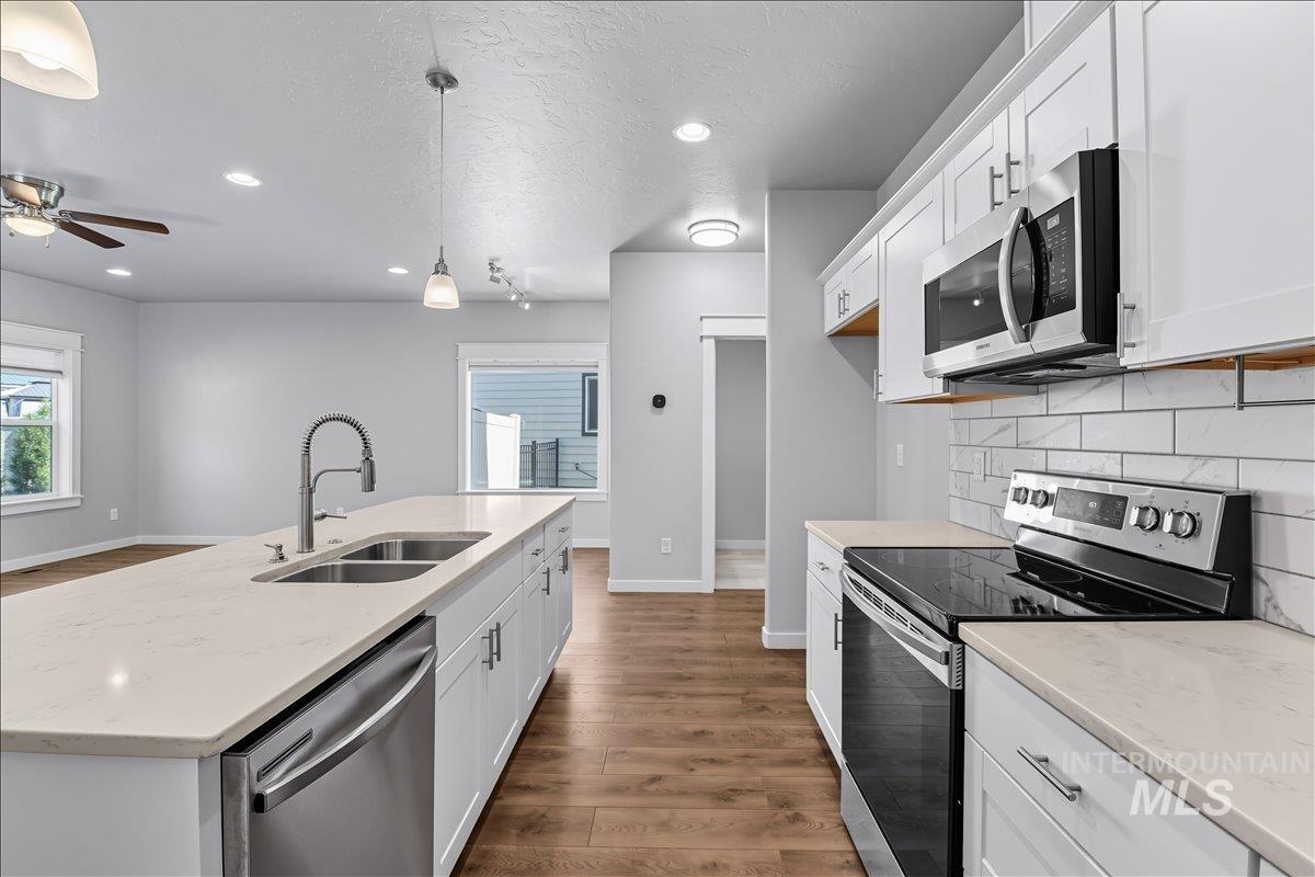 Kitchen featuring stainless steel appliances, dark wood-style flooring, recessed lighting, white cabinetry, and tasteful backsplash