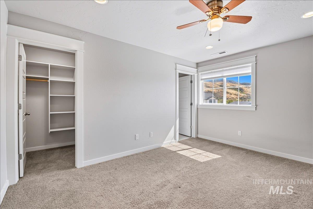 Unfurnished bedroom with a spacious closet, light carpet, ceiling fan, and recessed lighting
