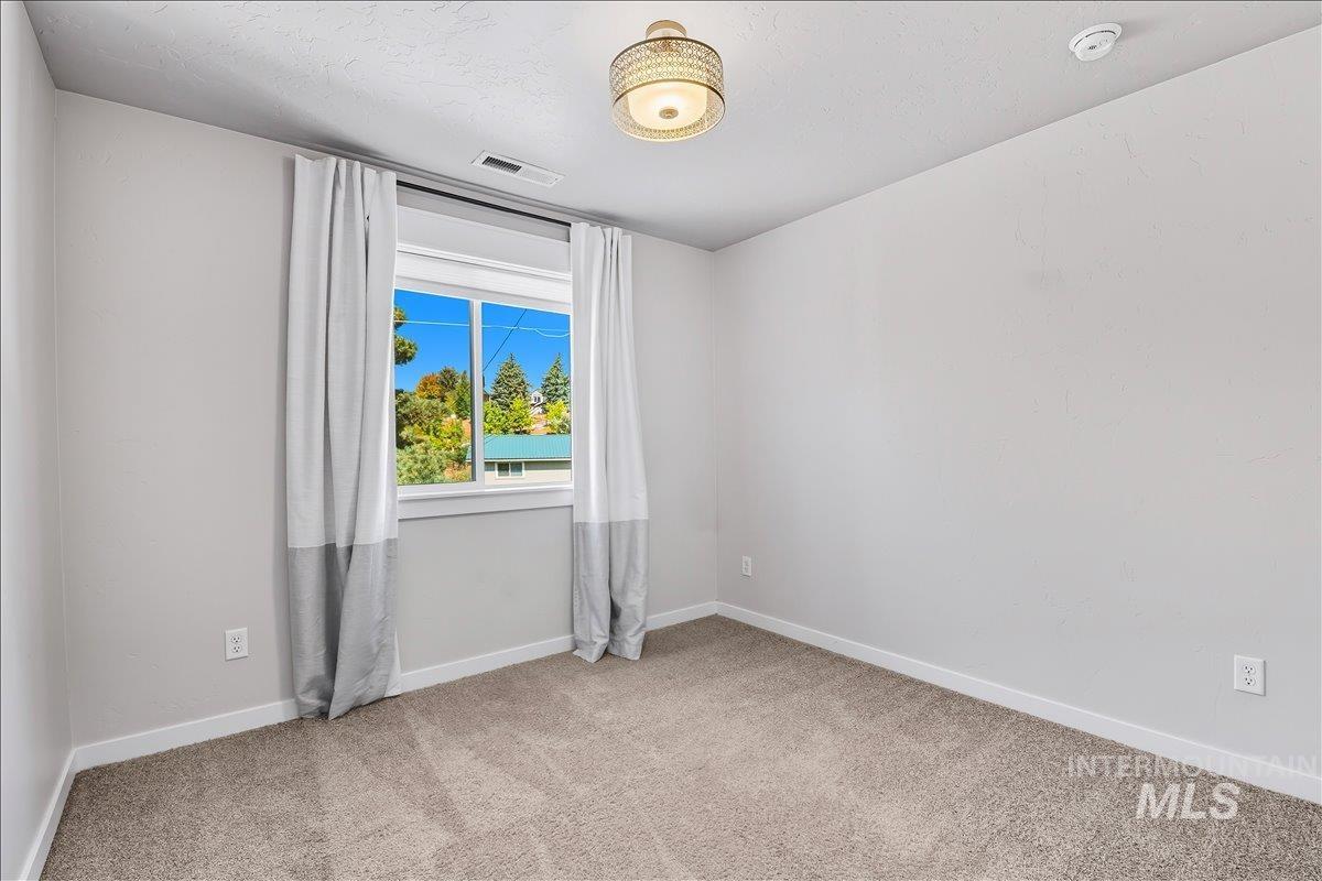 Empty room featuring light colored carpet and baseboards