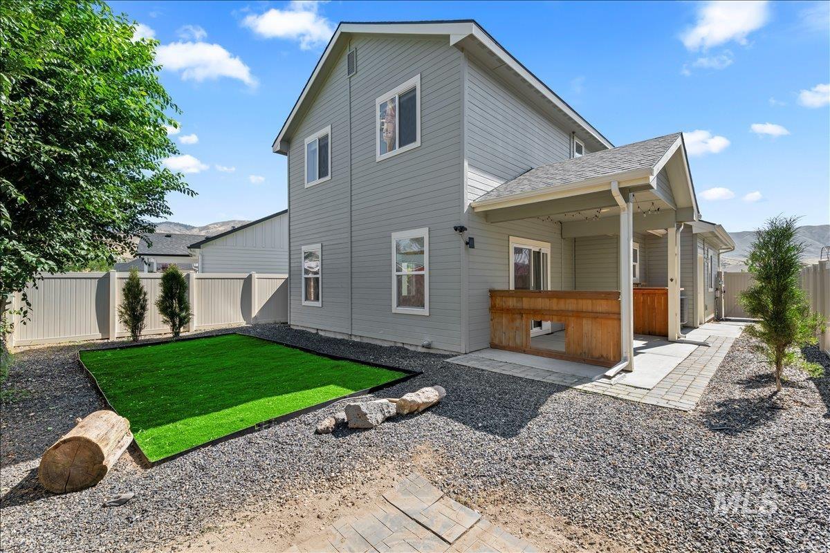 Rear view of house featuring a fenced backyard, a shingled roof, and a patio area