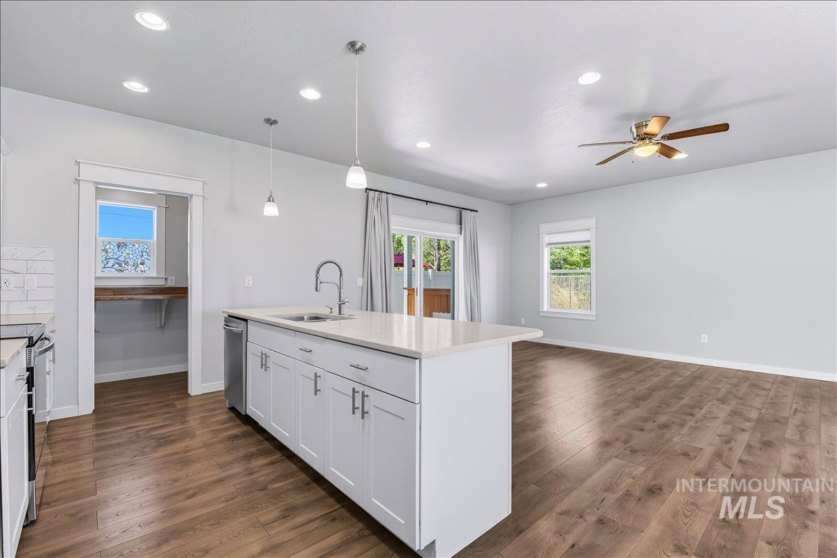 Kitchen with decorative light fixtures, a center island with sink, recessed lighting, dark wood-type flooring, and white cabinetry