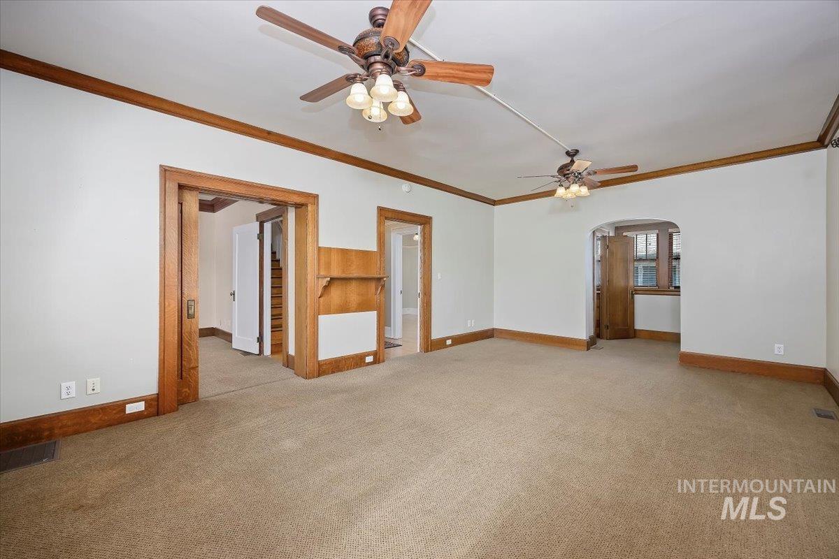 Spare room with ornamental molding, carpet flooring, arched walkways, and ceiling fan