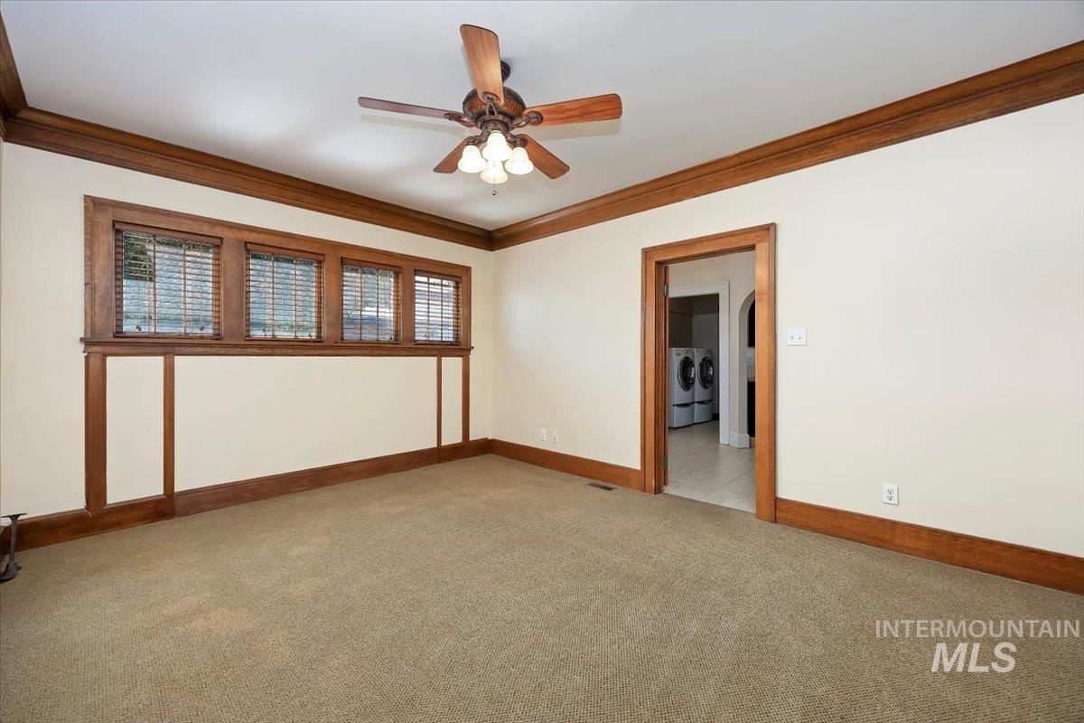 Carpeted spare room featuring crown molding and a ceiling fan