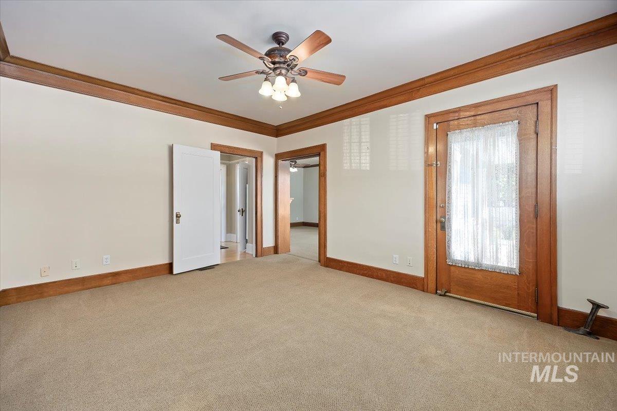 Empty room with crown molding, carpet flooring, and a ceiling fan