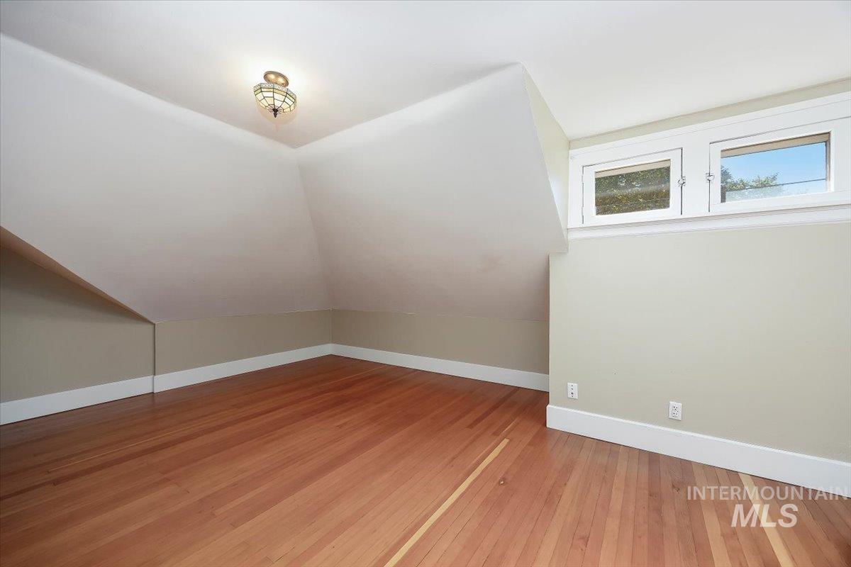 Additional living space featuring light wood-style flooring and lofted ceiling