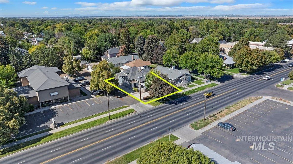 Aerial view of property and surrounding area with property parcel outlined and a heavily wooded area