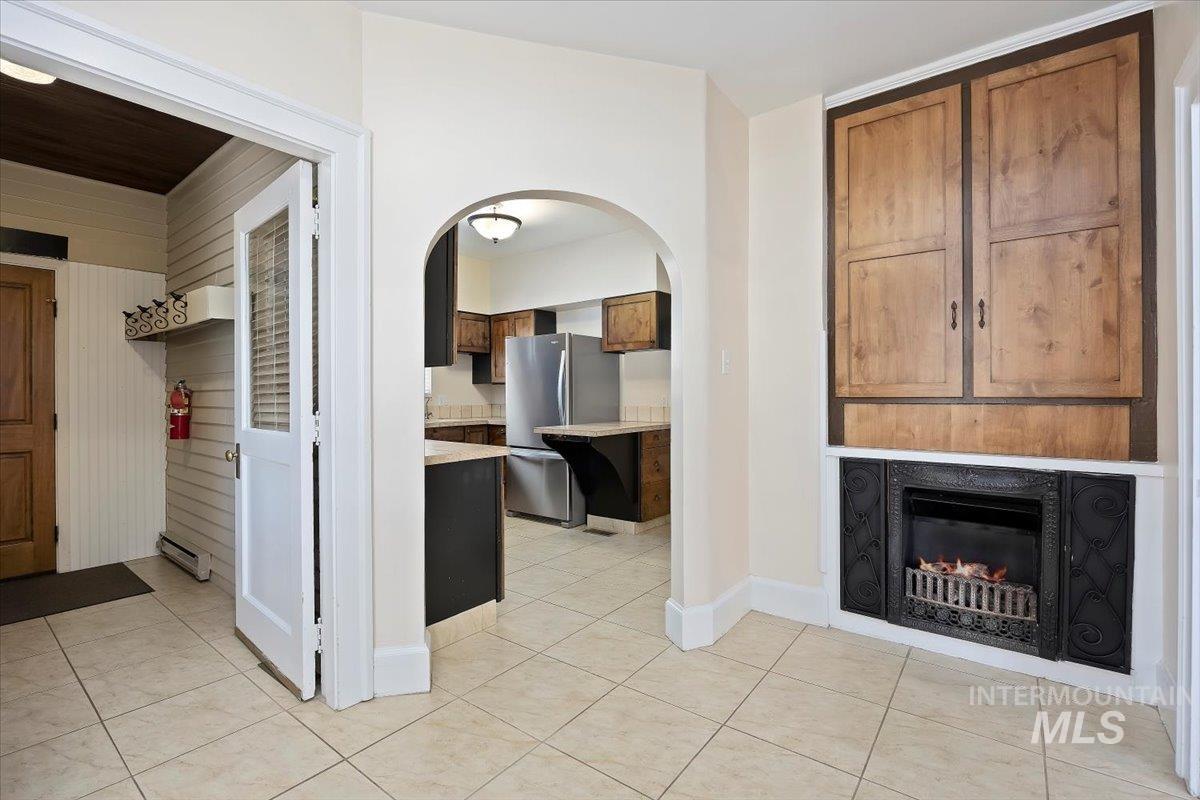 Unfurnished living room with light tile patterned flooring and a lit fireplace