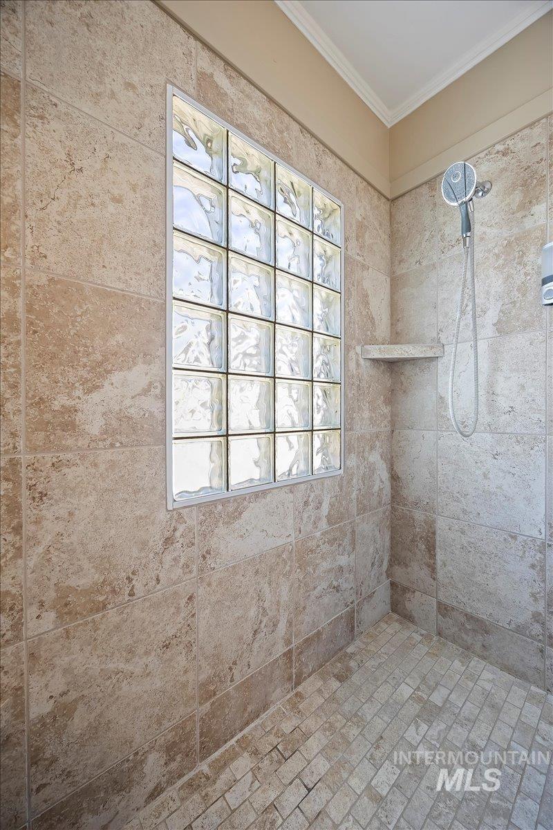Bathroom with a tile shower and crown molding