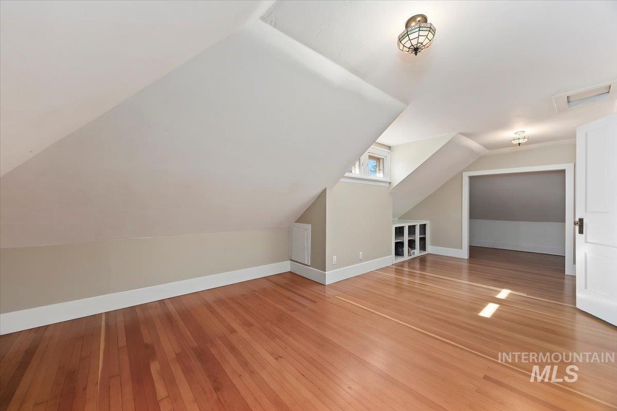 Bonus room featuring light wood-type flooring, lofted ceiling, and attic access