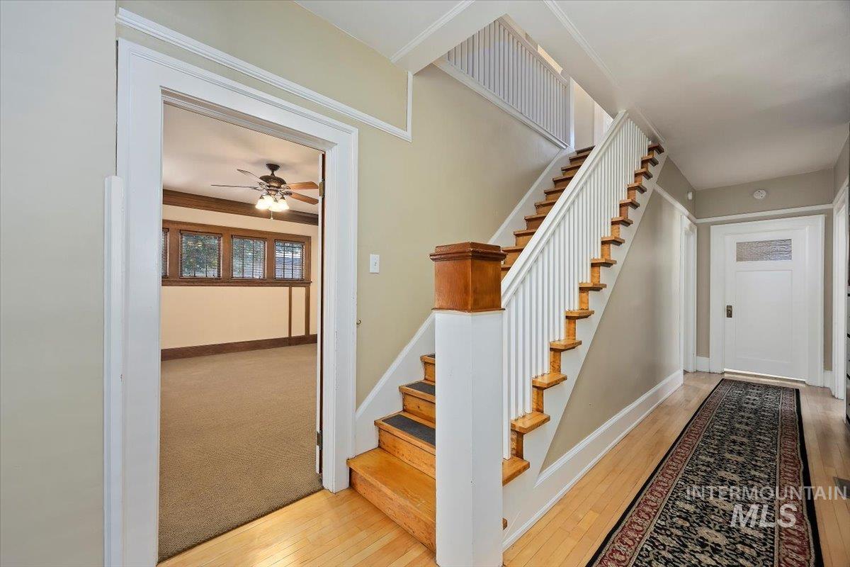 Stairway with hardwood / wood-style floors and a ceiling fan