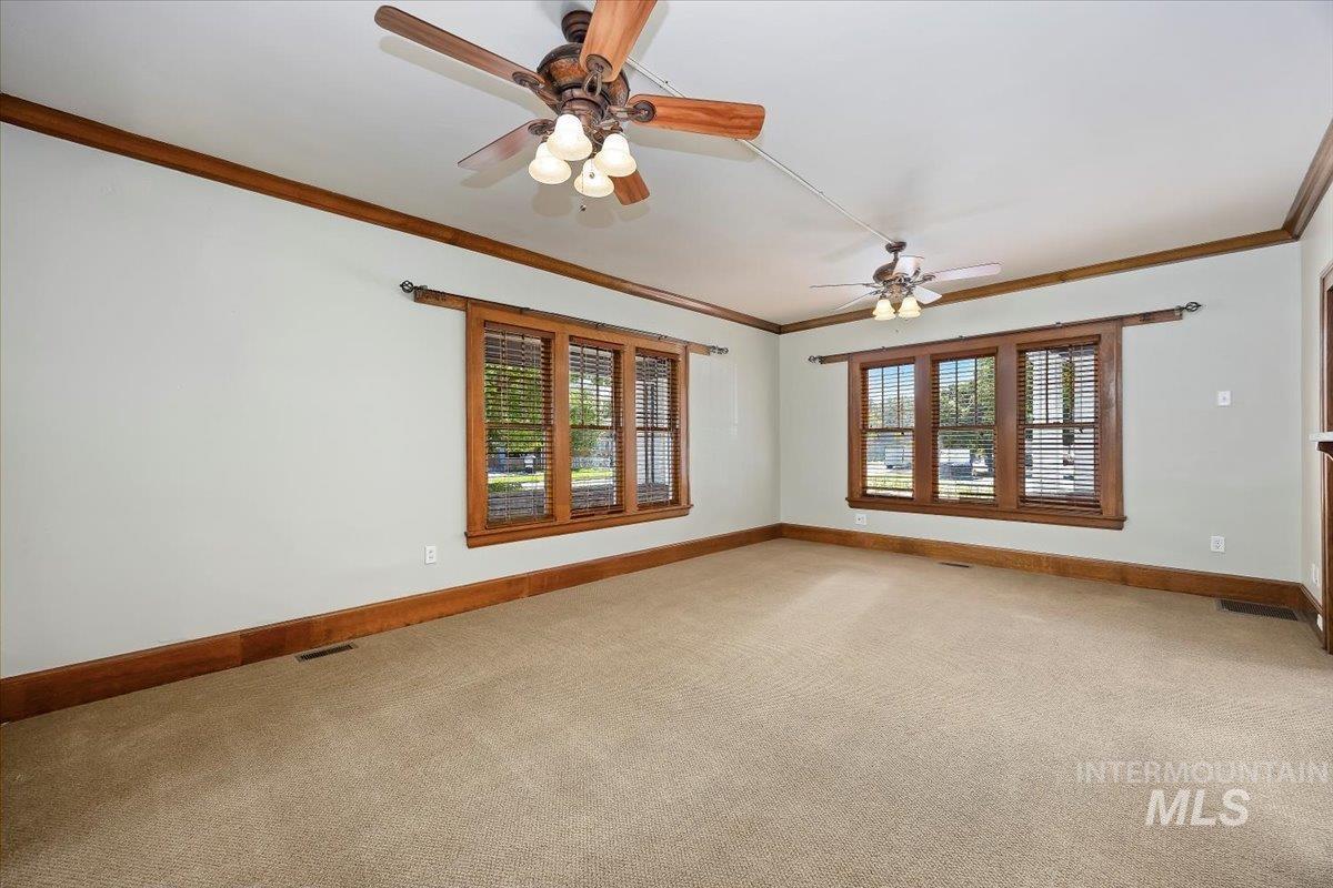 Carpeted spare room with ornamental molding and a ceiling fan