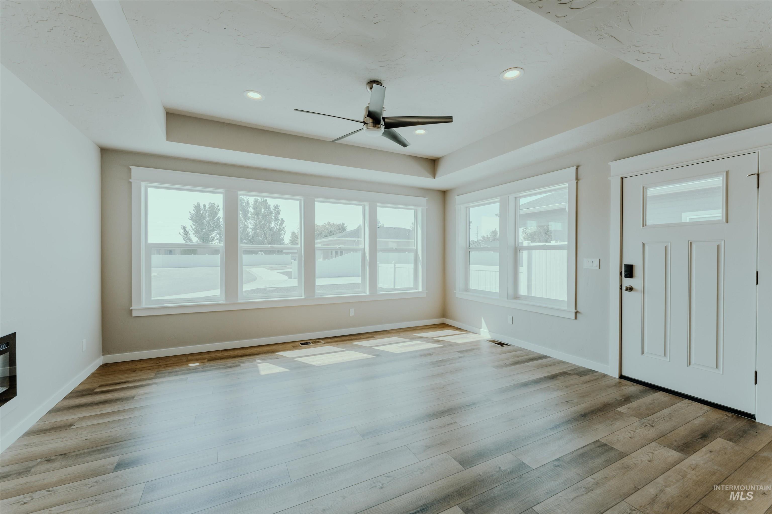 Foyer entrance with a tray ceiling, ceiling fan, light wood-style floors, and recessed lighting