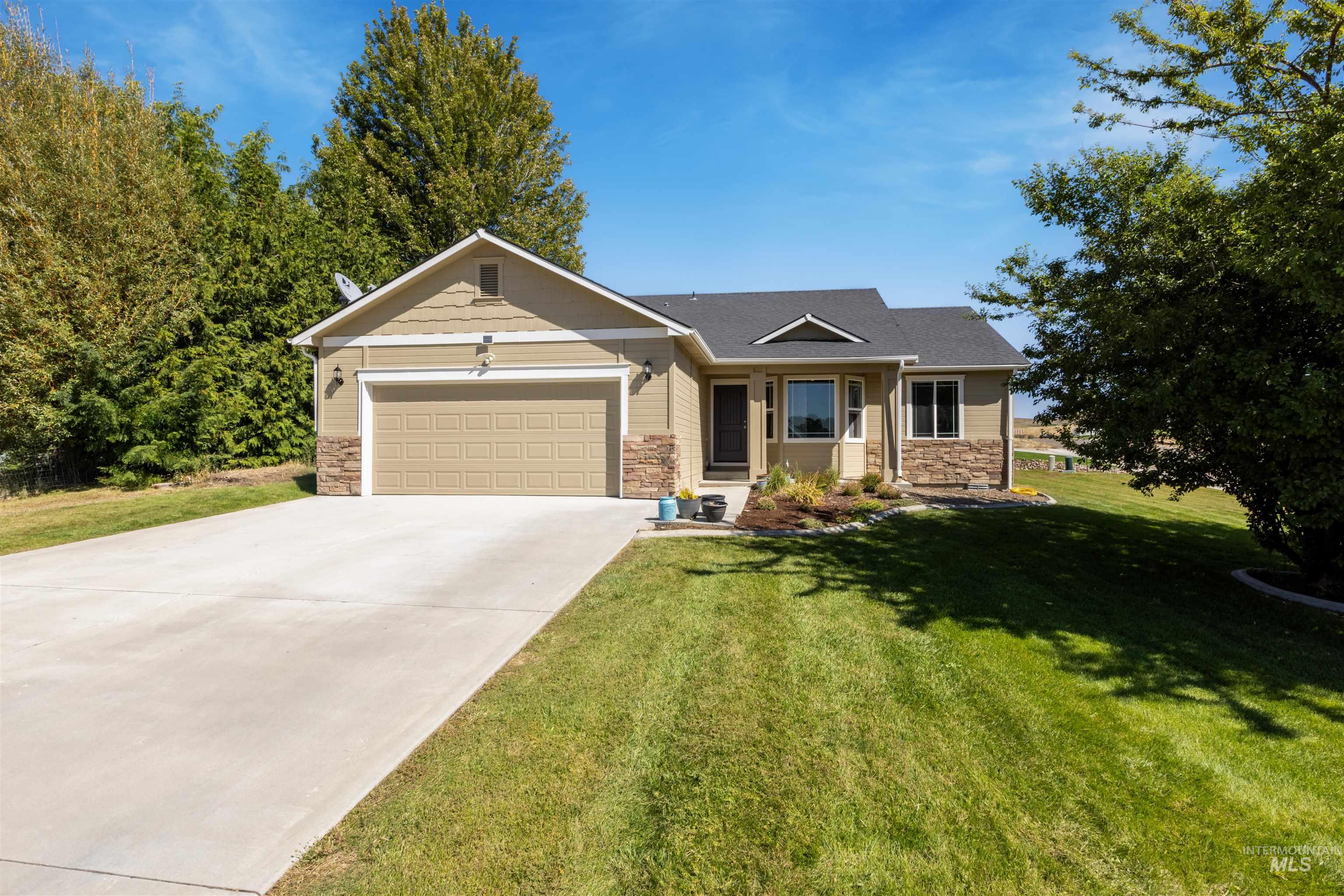 View of front of house featuring stone siding, driveway, a front yard, and a garage