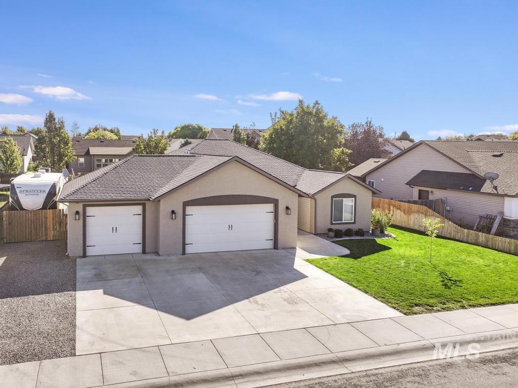 View of front of home with stucco siding, a garage, driveway, and a residential view