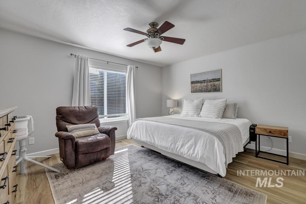 Bedroom with light wood-style flooring, a textured ceiling, and a ceiling fan