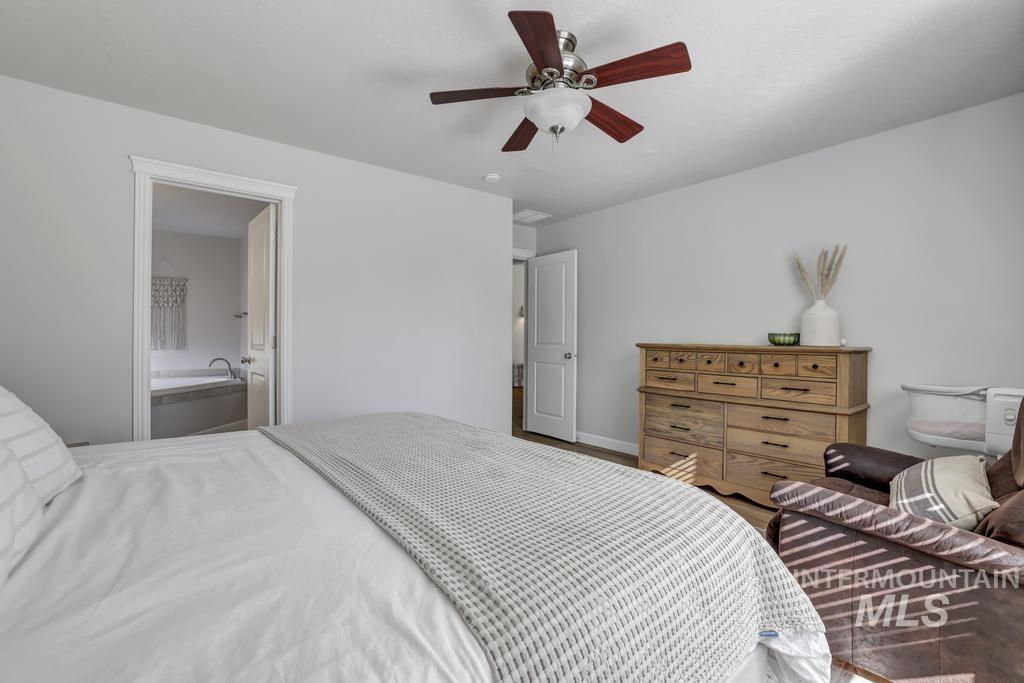 Bedroom with a ceiling fan, wood finished floors, and ensuite bath