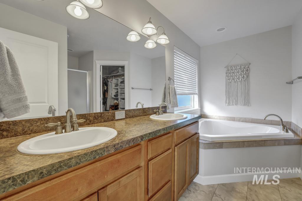 Bathroom with a stall shower, a walk in closet, double vanity, and a garden tub