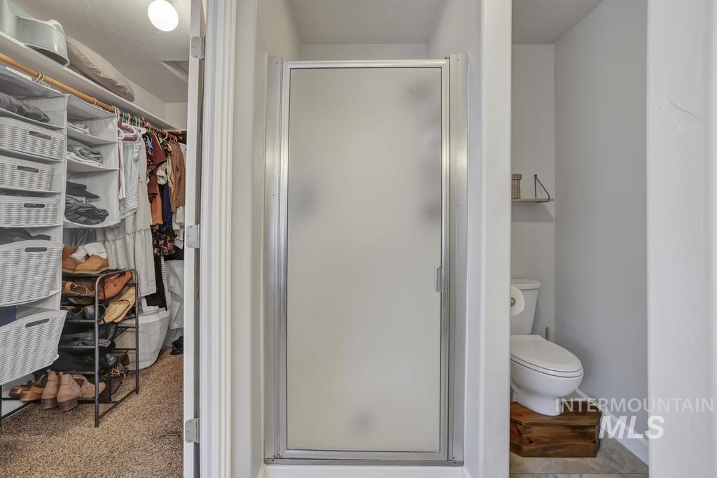 Bathroom featuring a spacious closet and a shower stall
