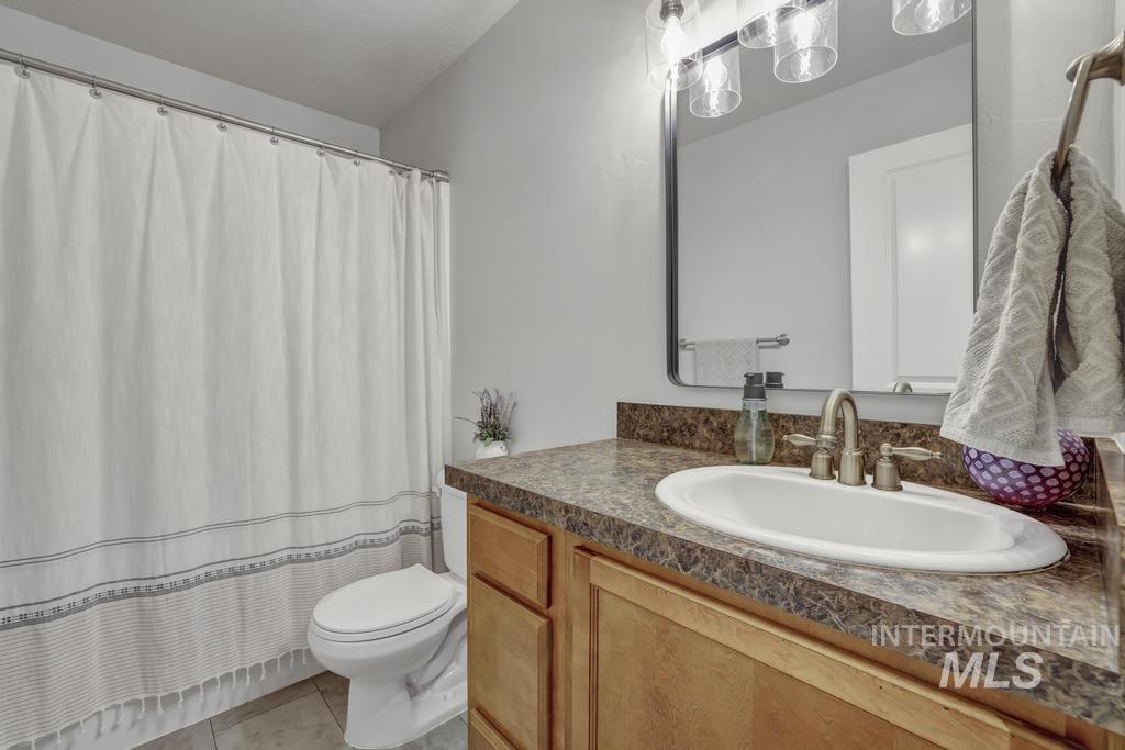 Full bathroom with vanity, light tile patterned floors, and curtained shower
