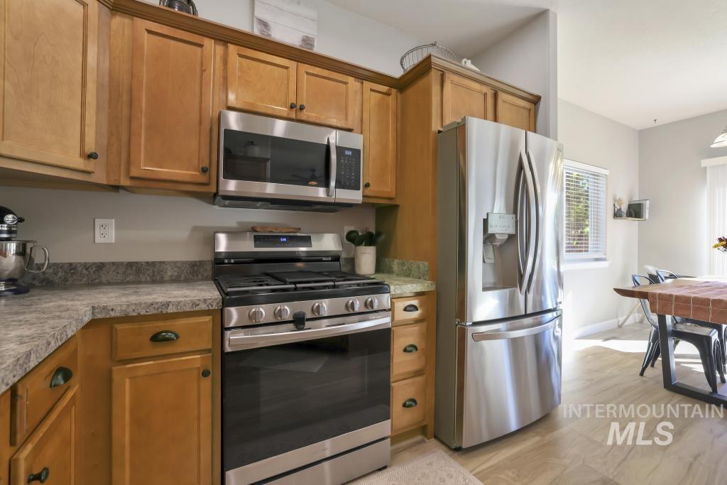 Kitchen with appliances with stainless steel finishes, brown cabinetry, and light countertops