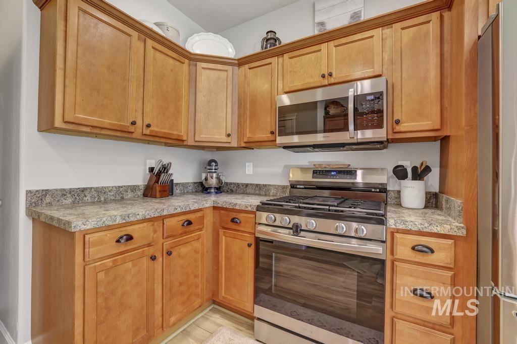 Kitchen with appliances with stainless steel finishes, brown cabinetry, and light wood-style flooring