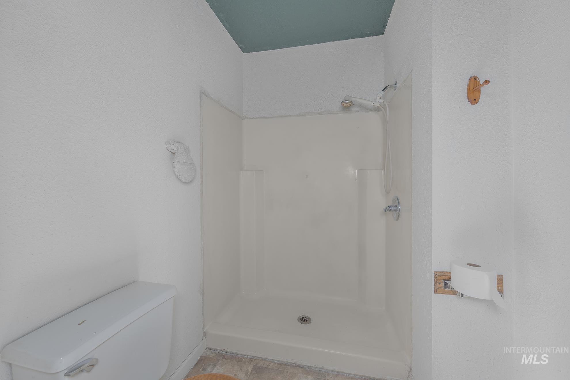 Bathroom featuring a shower stall and toilet