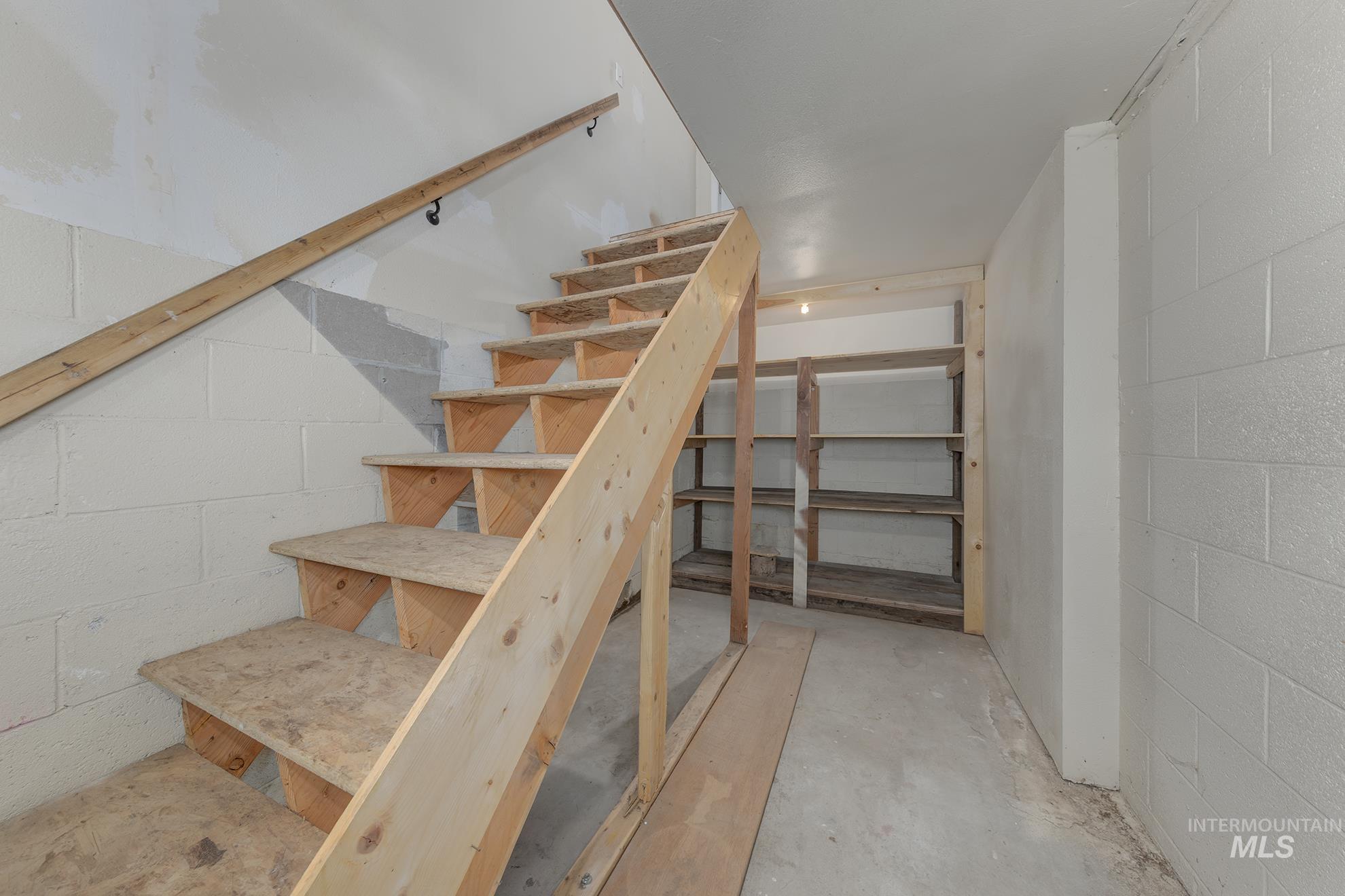 Staircase featuring unfinished concrete flooring