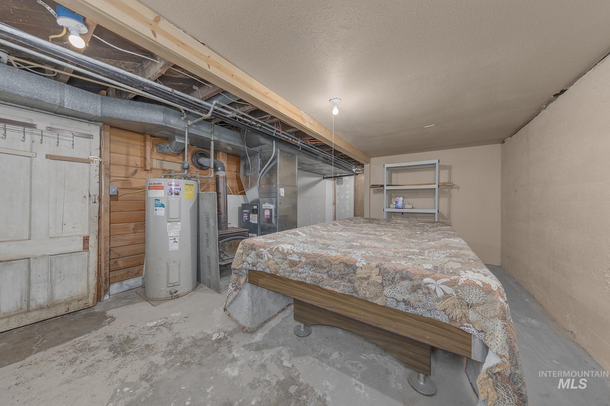 Bedroom with concrete flooring, electric water heater, and heating unit