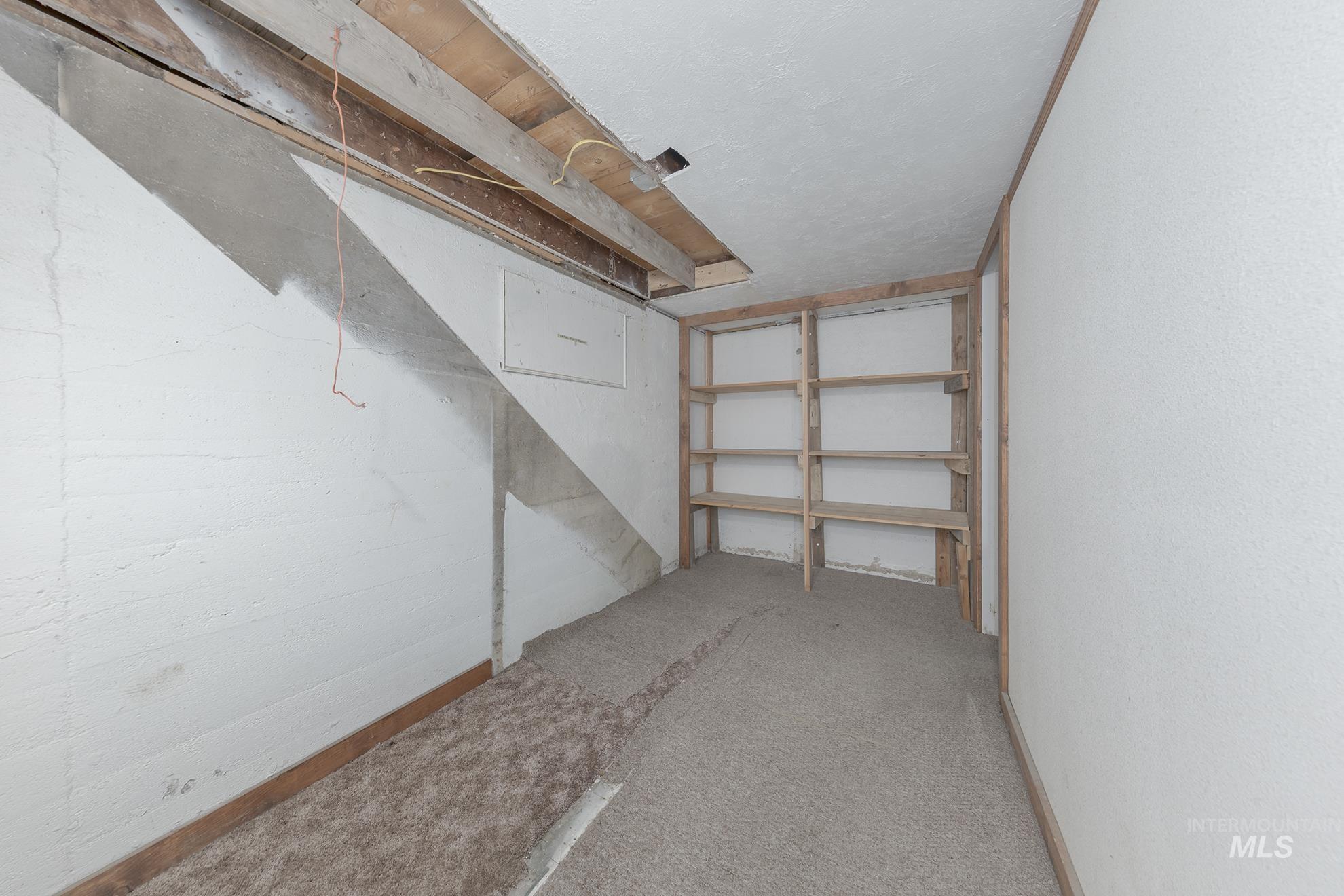 Unfinished below grade area featuring carpet floors and a textured ceiling