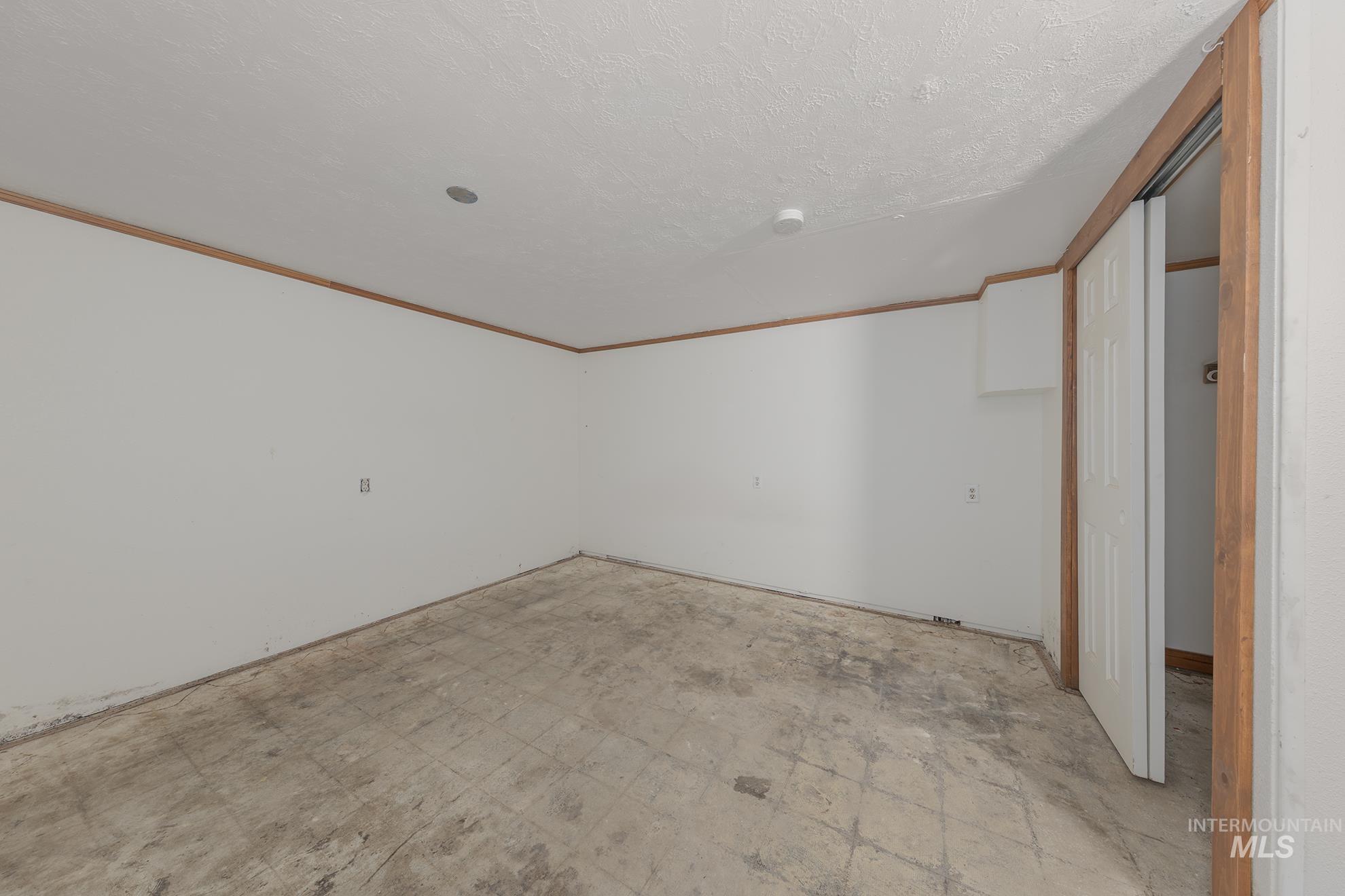 Empty room with crown molding and a textured ceiling
