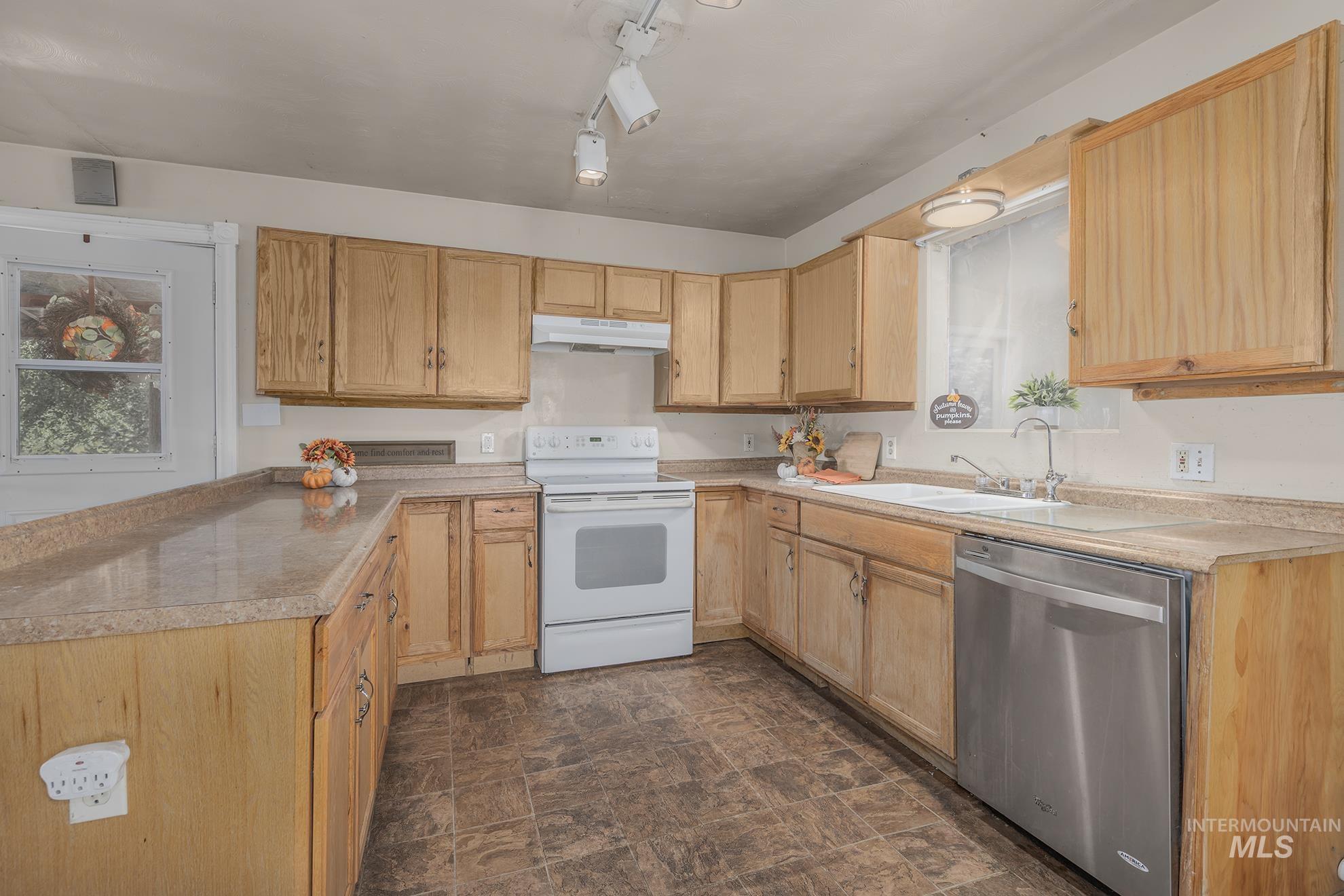 Kitchen with white range with electric cooktop, dishwasher, stone finish flooring, and light countertops