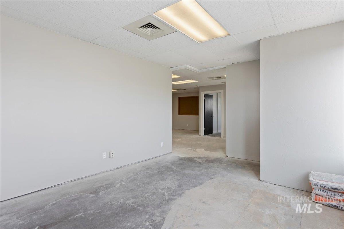 Unfurnished room with concrete floors and a drop ceiling