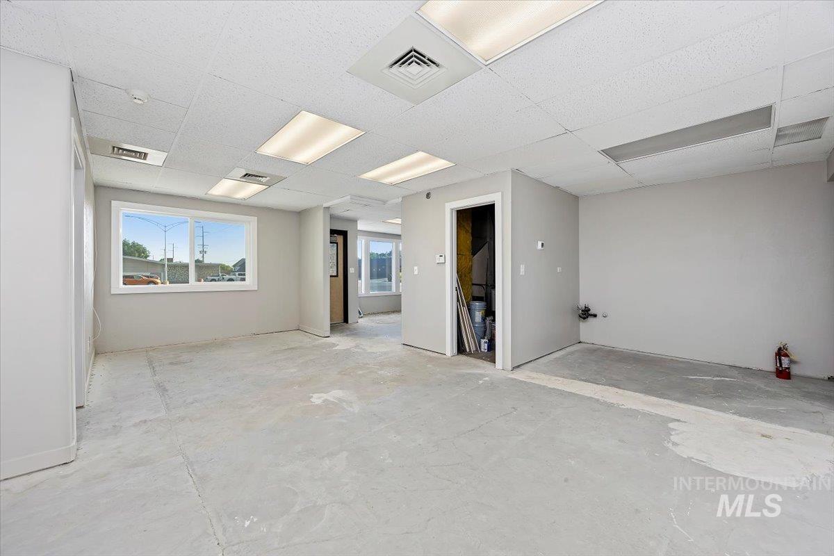 Empty room with a paneled ceiling and unfinished concrete floors