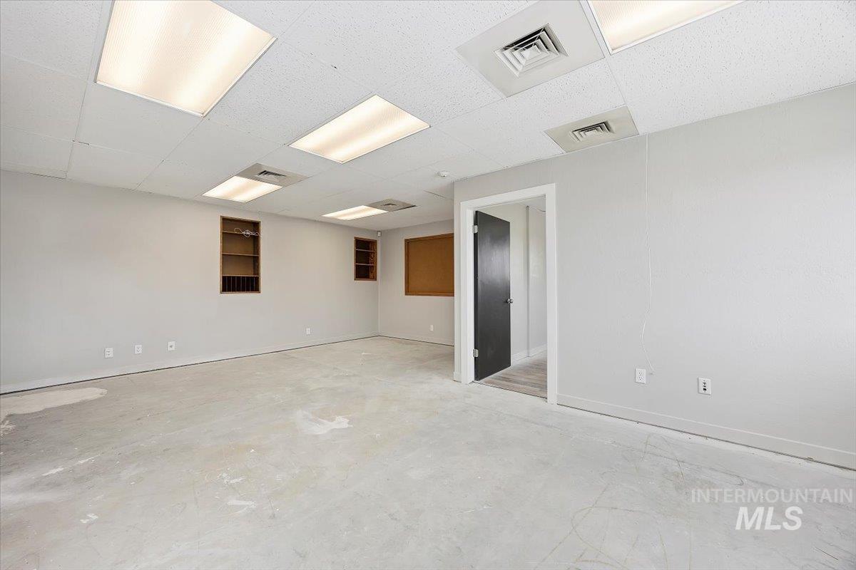 Unfurnished room featuring unfinished concrete floors and a paneled ceiling
