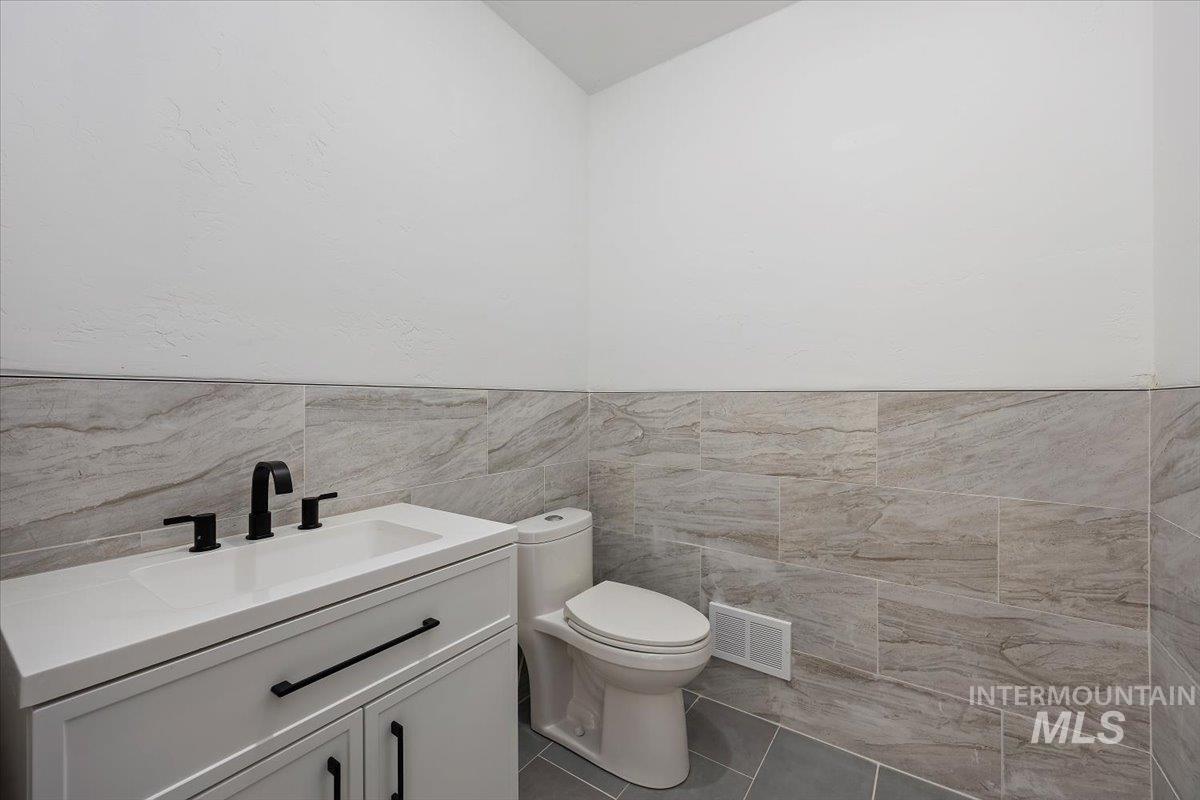 Bathroom with vanity, tile walls, tile patterned flooring, and a wainscoted wall