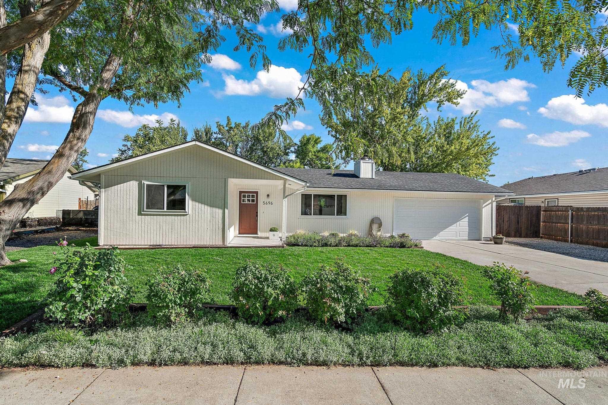 Ranch-style house with an attached garage, driveway, and a chimney