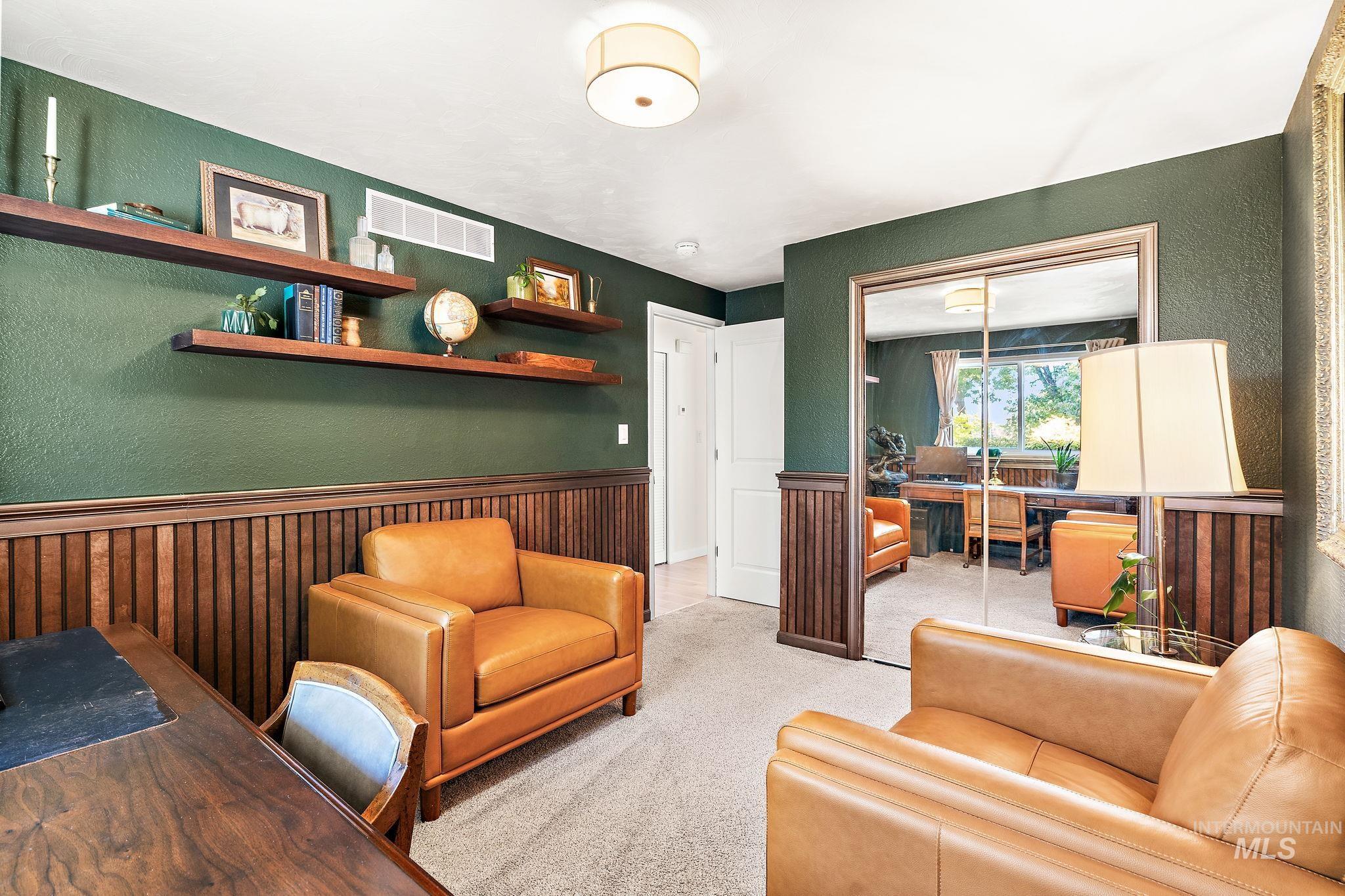 Carpeted home office with a textured wall, wainscoting, and wood walls