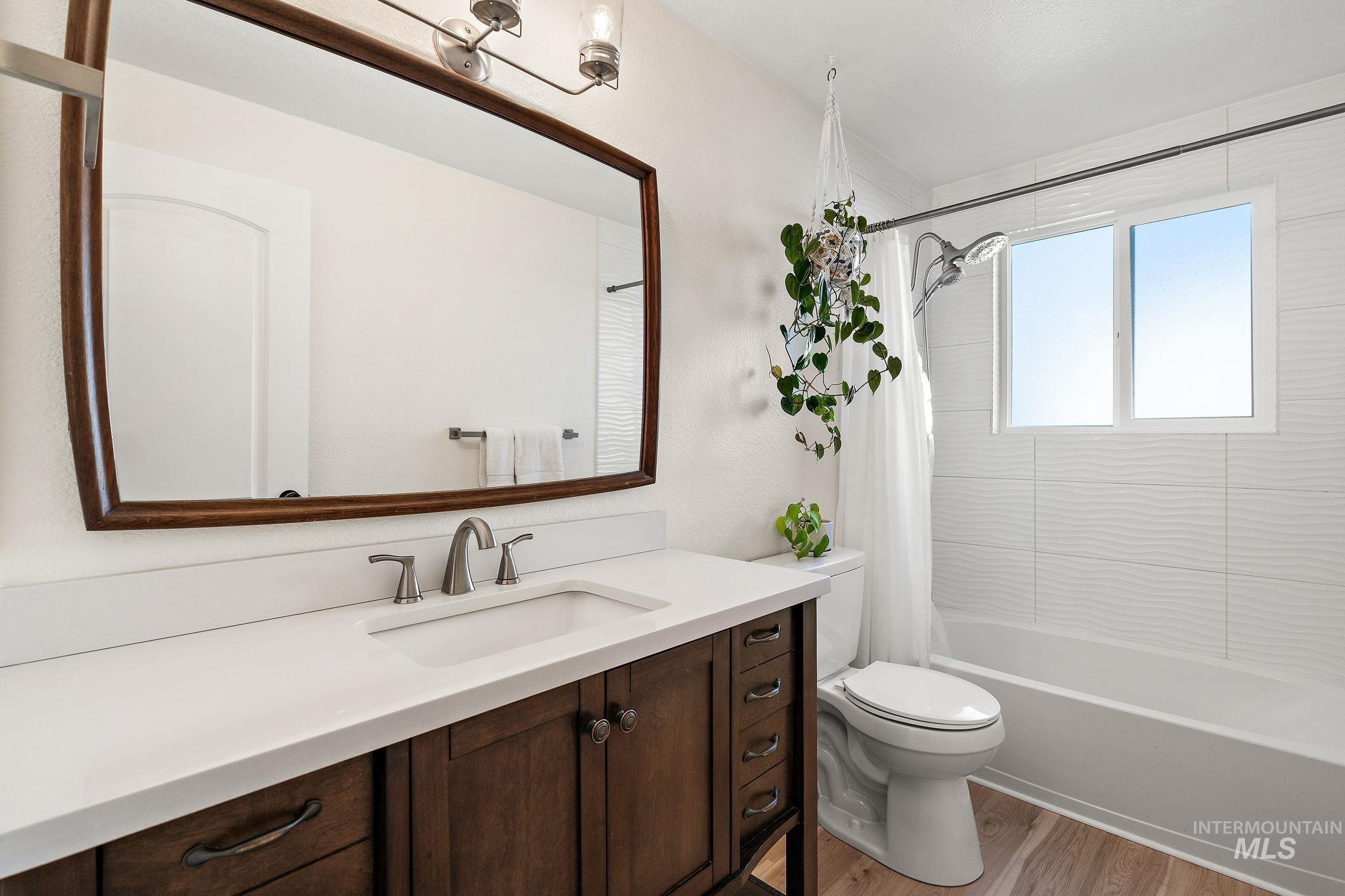 Full bath featuring shower / tub combo, light wood-style floors, and vanity