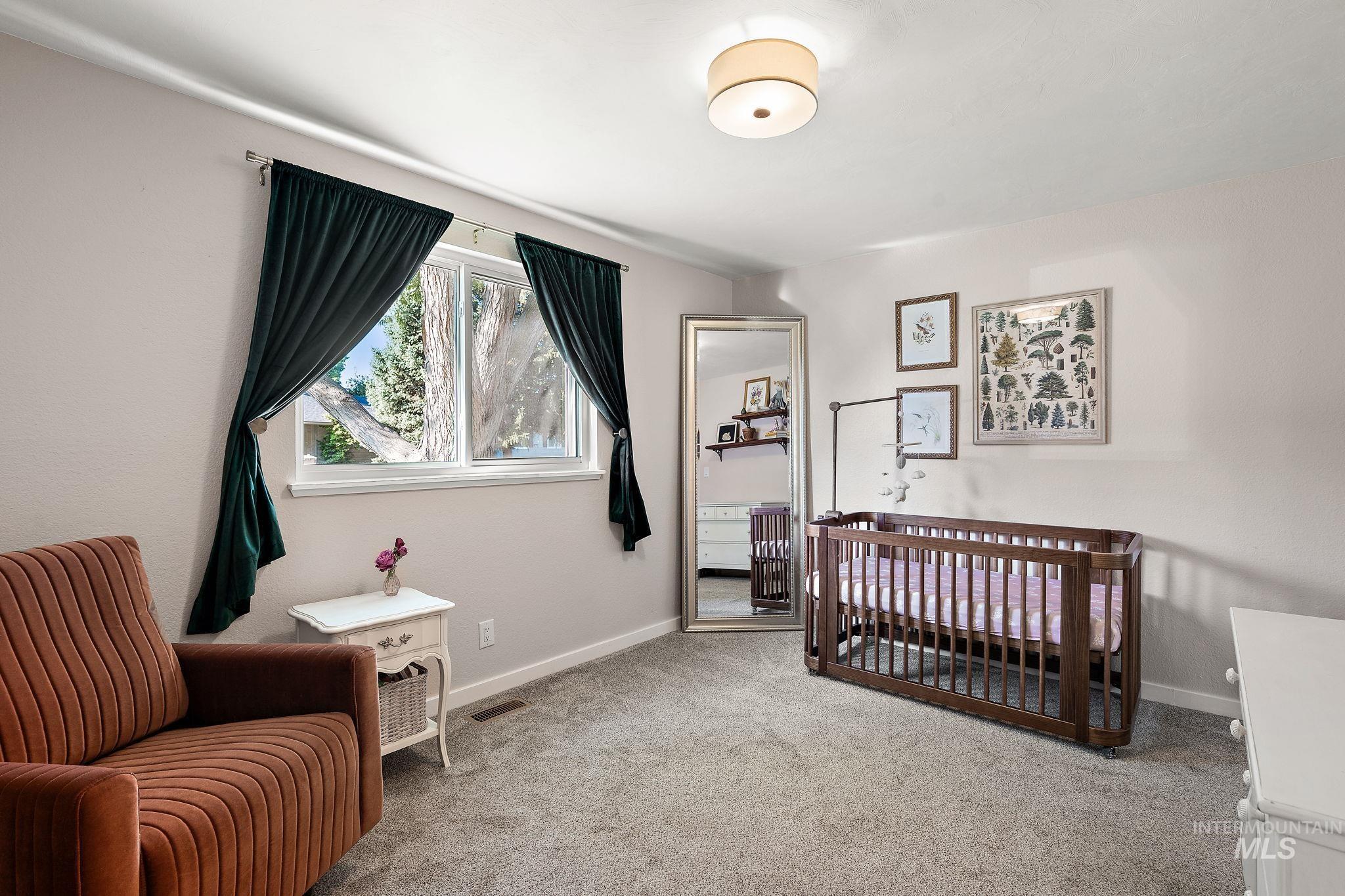 Bedroom featuring a crib and light colored carpet