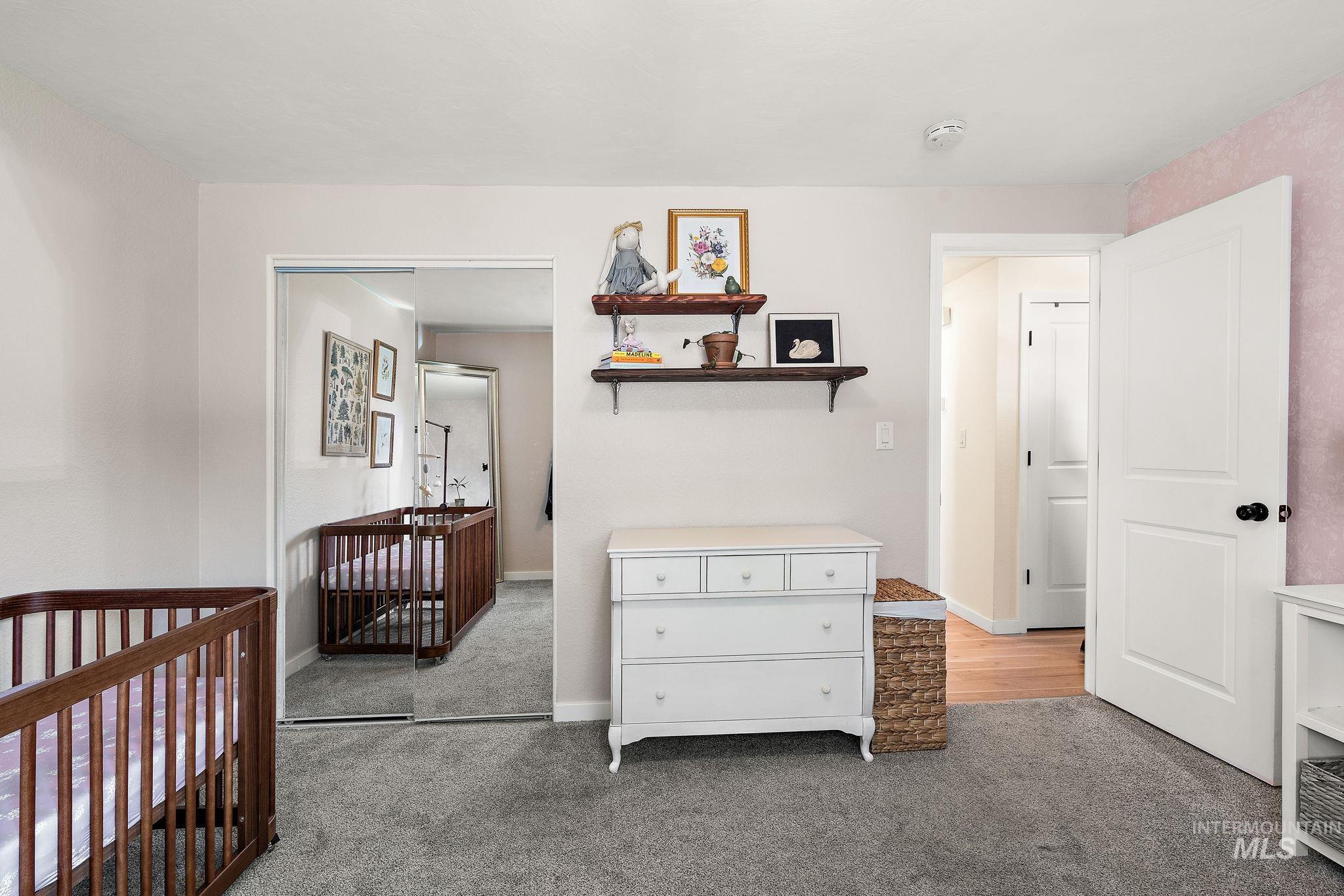 Bedroom featuring light carpet and a nursery area